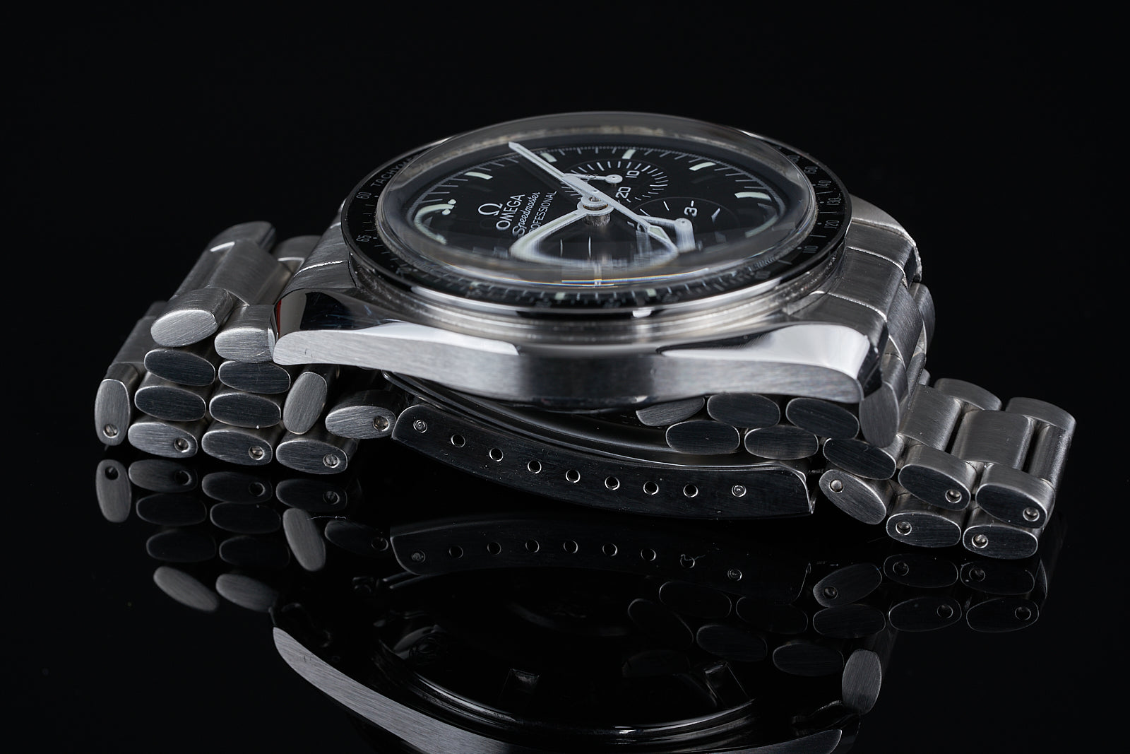 Omega Speedmaster professional chronograph watch with stainless steel bracelet and black dial on black background