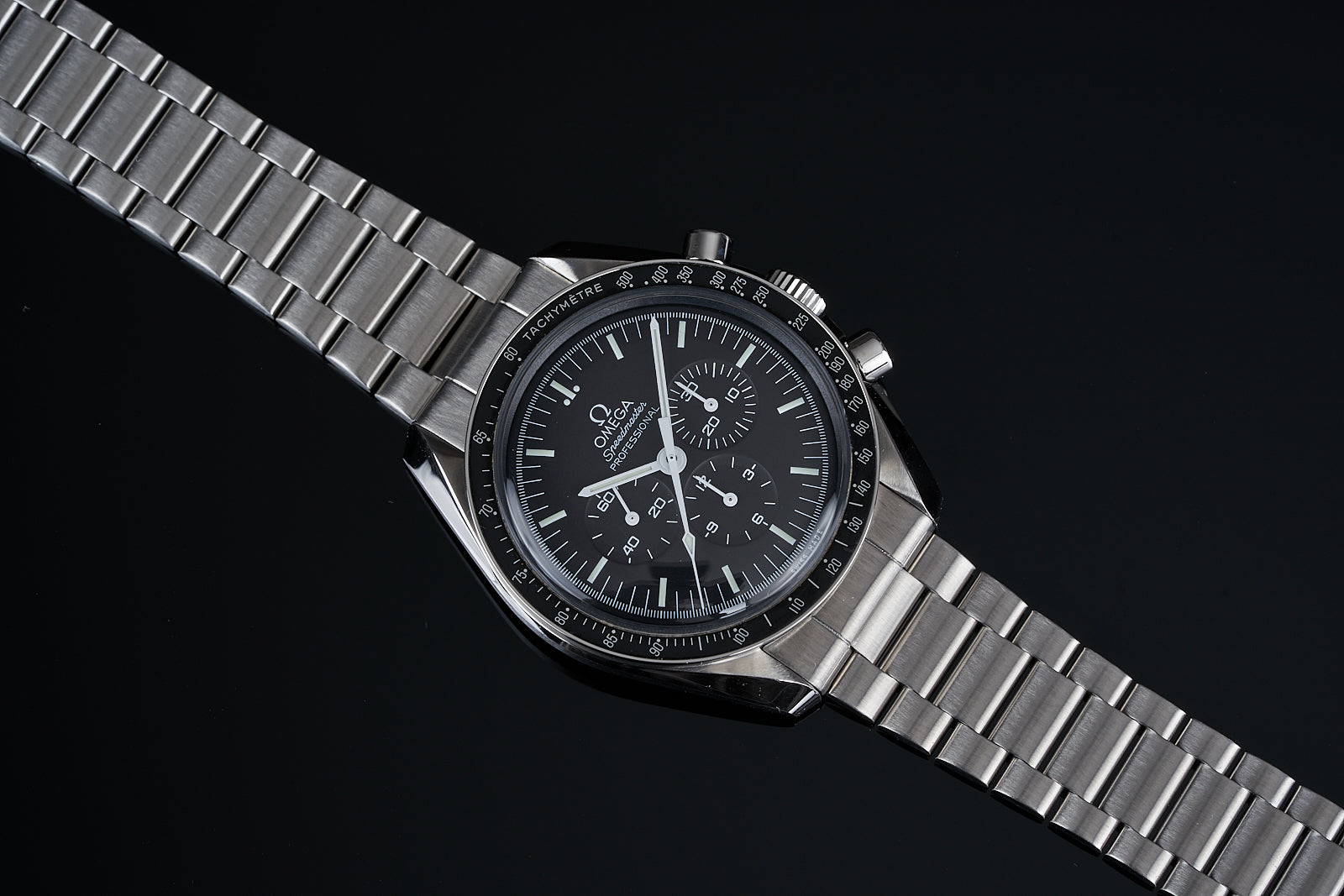 Omega Speedmaster chronograph watch with stainless steel bracelet and black dial on dark background