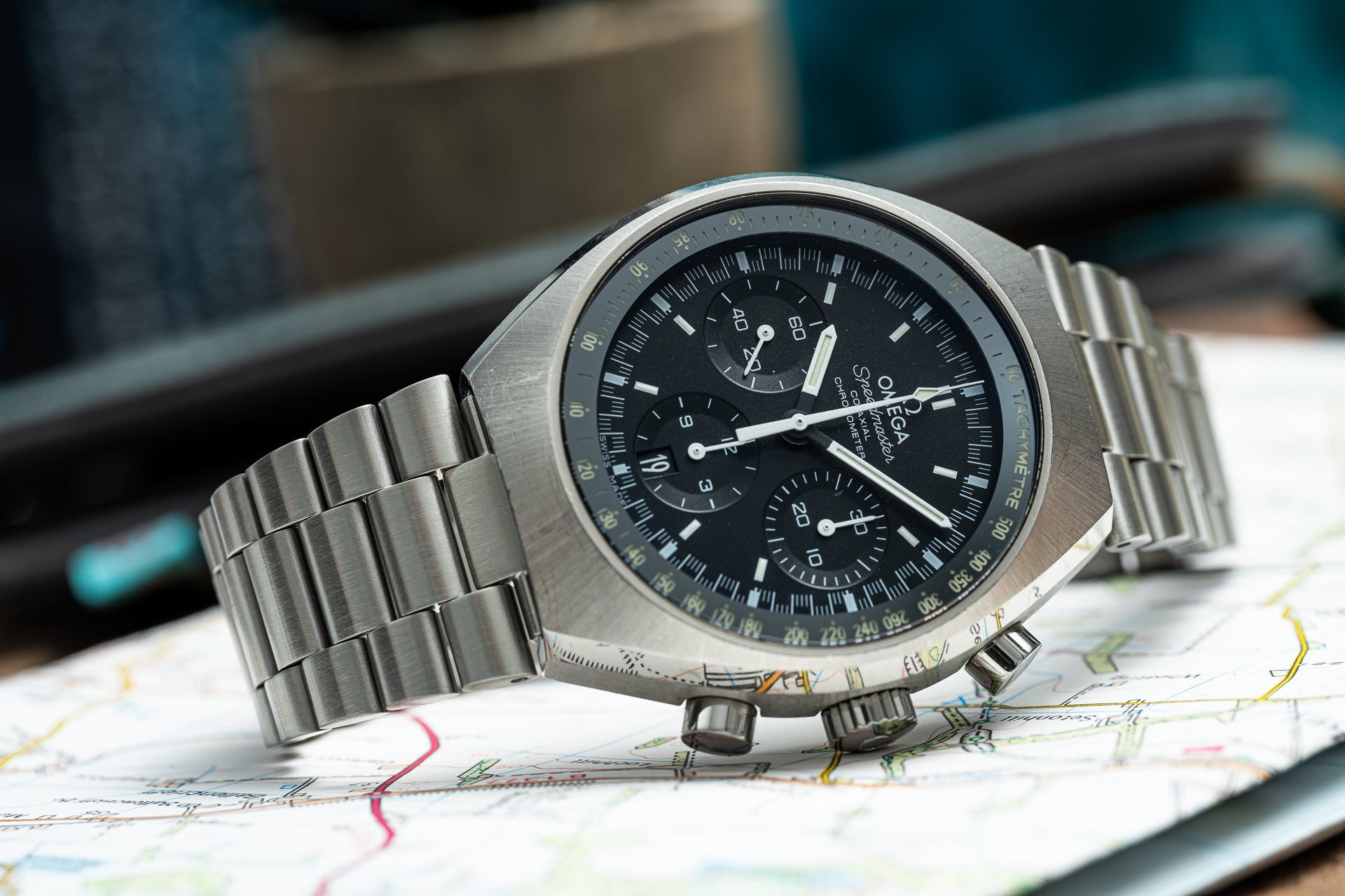 Omega Speedmaster Mark II chronograph watch with stainless steel bracelet on road map background