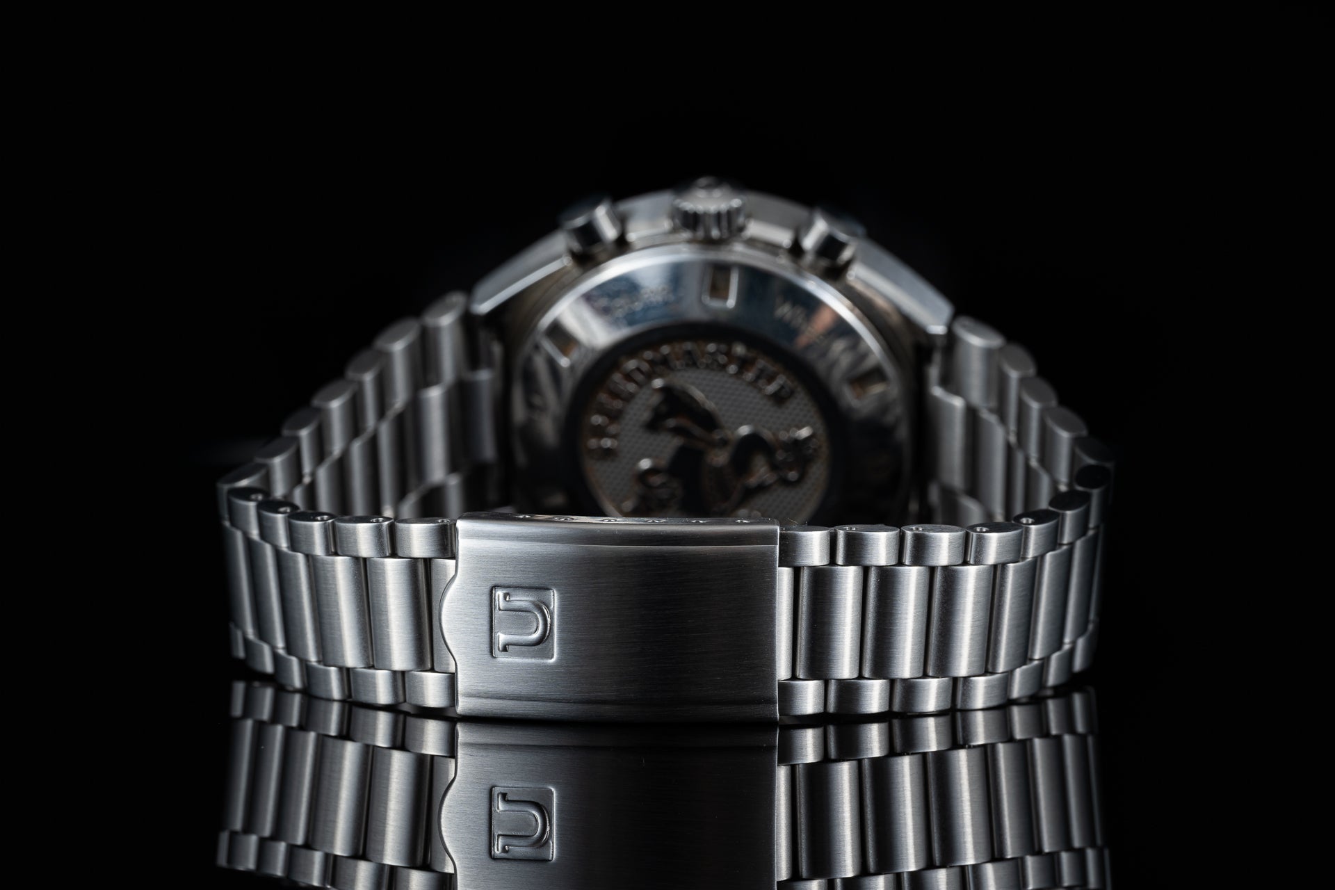 Stainless steel bracelet watch with linked metal band and logo clasp, front view on black background