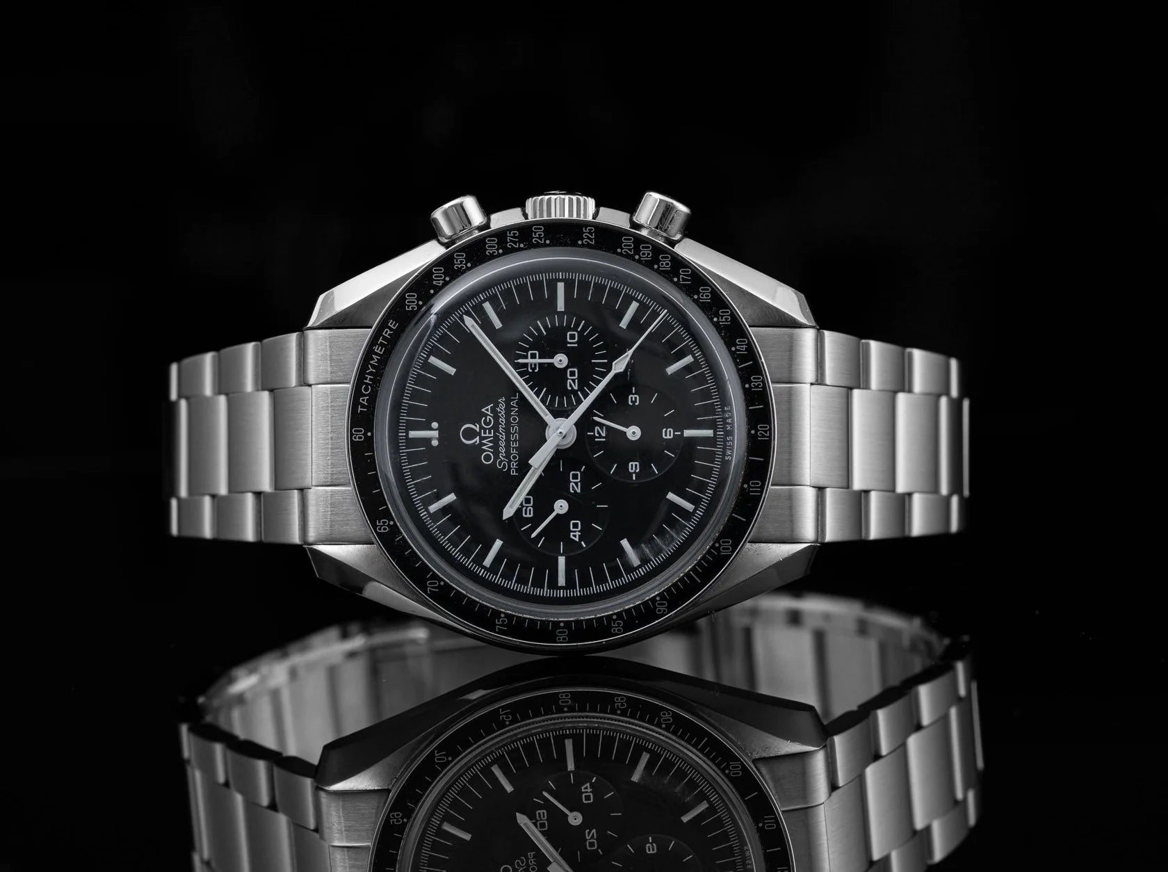 Omega Speedmaster Professional chronograph watch with stainless steel bracelet and black dial on reflective surface