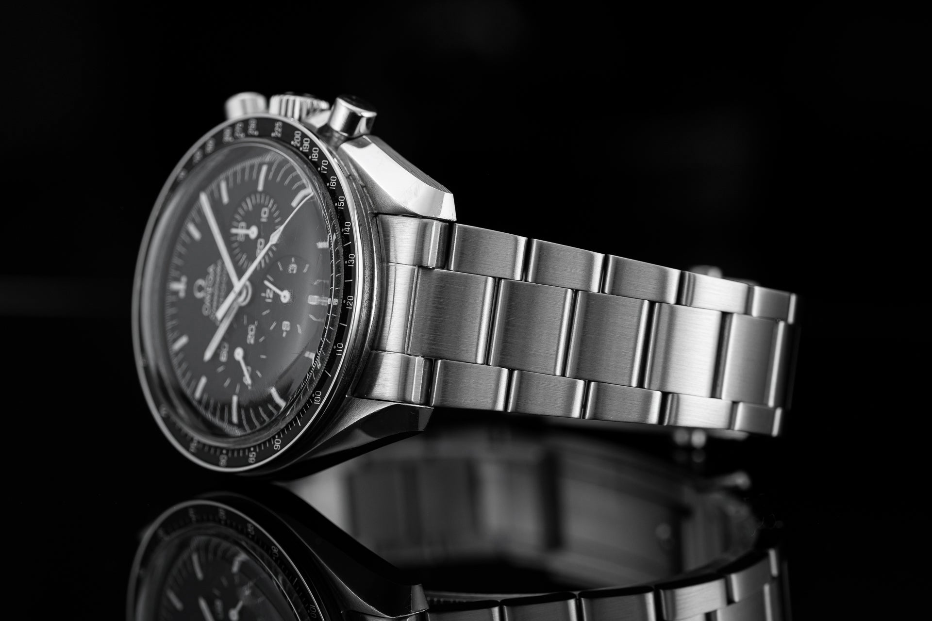Silver chronograph watch with black dial and stainless steel bracelet on black background