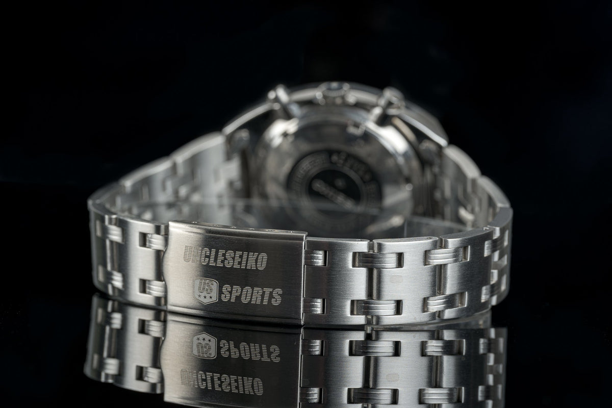 Stainless steel sports watch bracelet with engraved clasp, polished links, three-row design on black background
