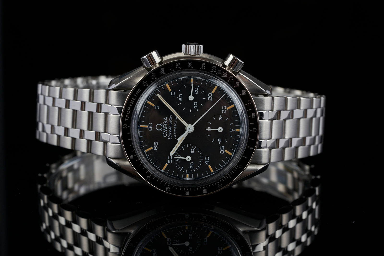 Omega Speedmaster Reduced chronograph watch with black dial, orange accents, steel bracelet on black background
