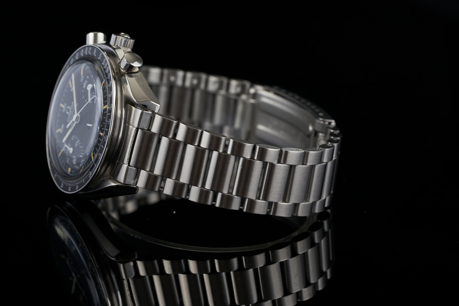 Stainless steel bracelet watch with black dial, chronograph subdials, and polished metal link band on black background