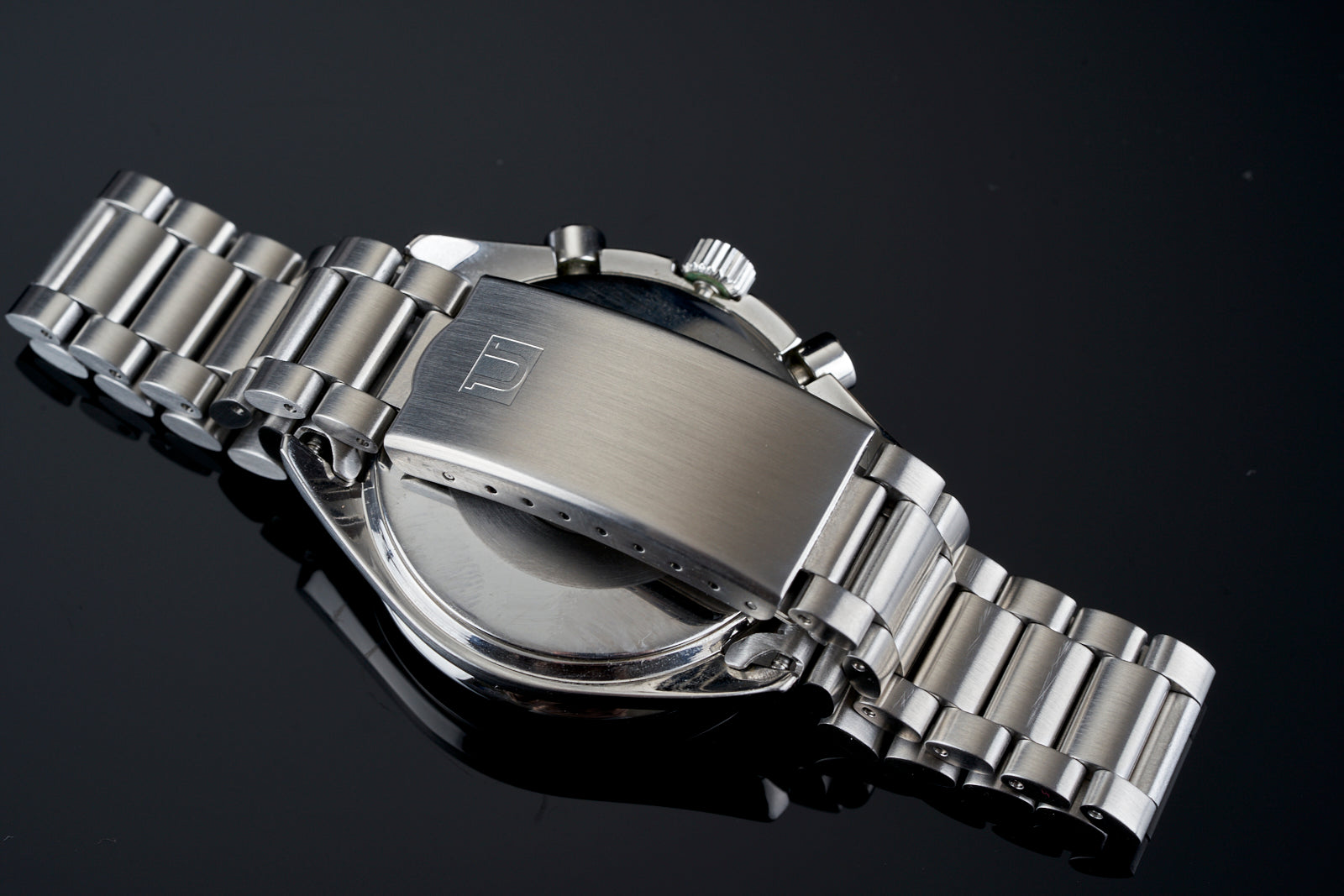 Stainless steel chronograph watch with rectangular case, brushed dial, and integrated three-link metal bracelet on dark background