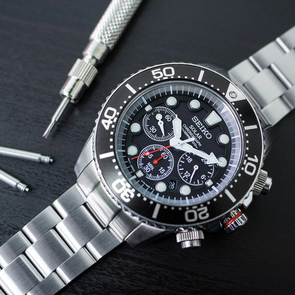 Seiko Solar SSC015 chronograph watch with stainless steel Super-O Boyer bracelet and black dial, displayed with watch tools