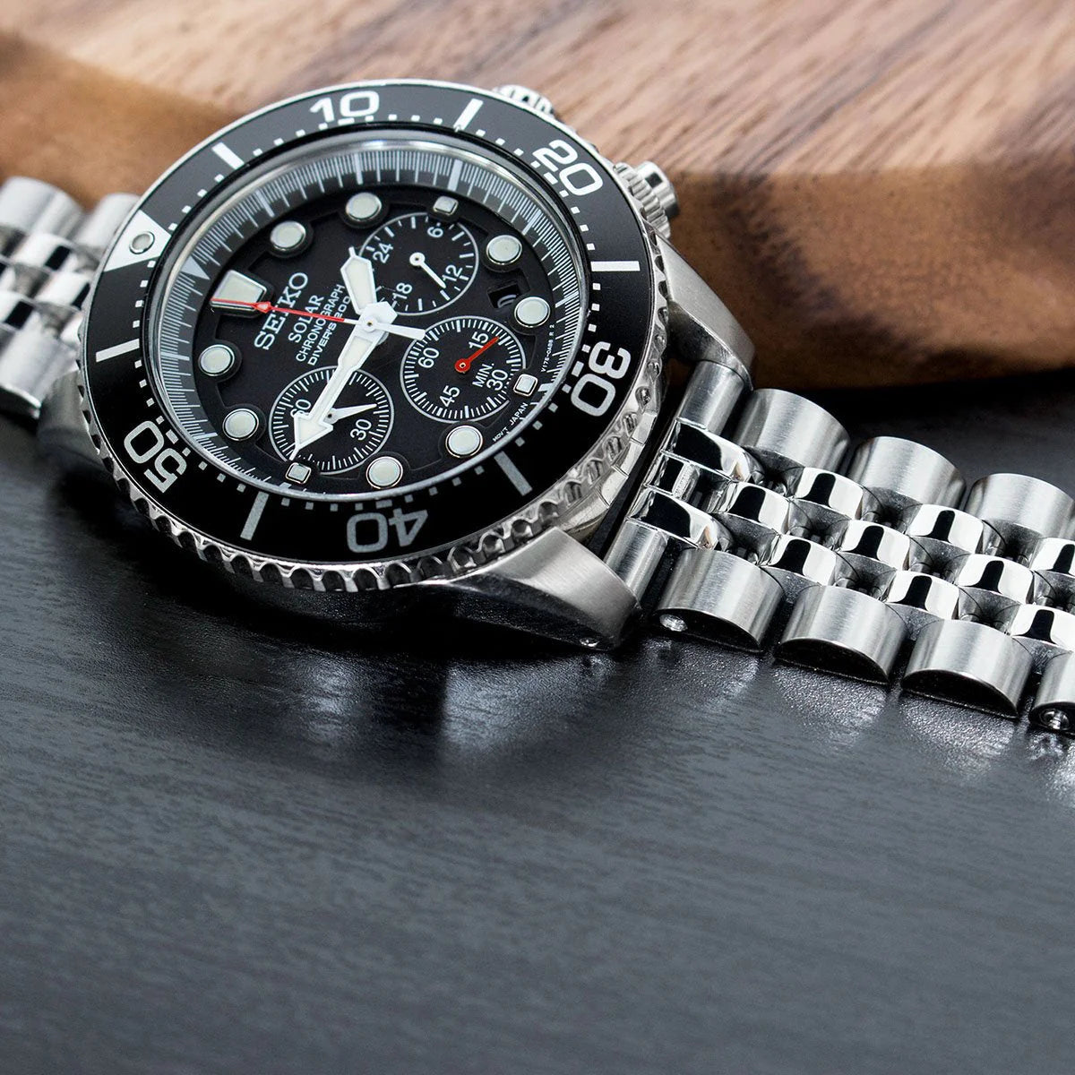 Seiko chronograph dive watch with black dial and stainless steel bracelet on wooden background