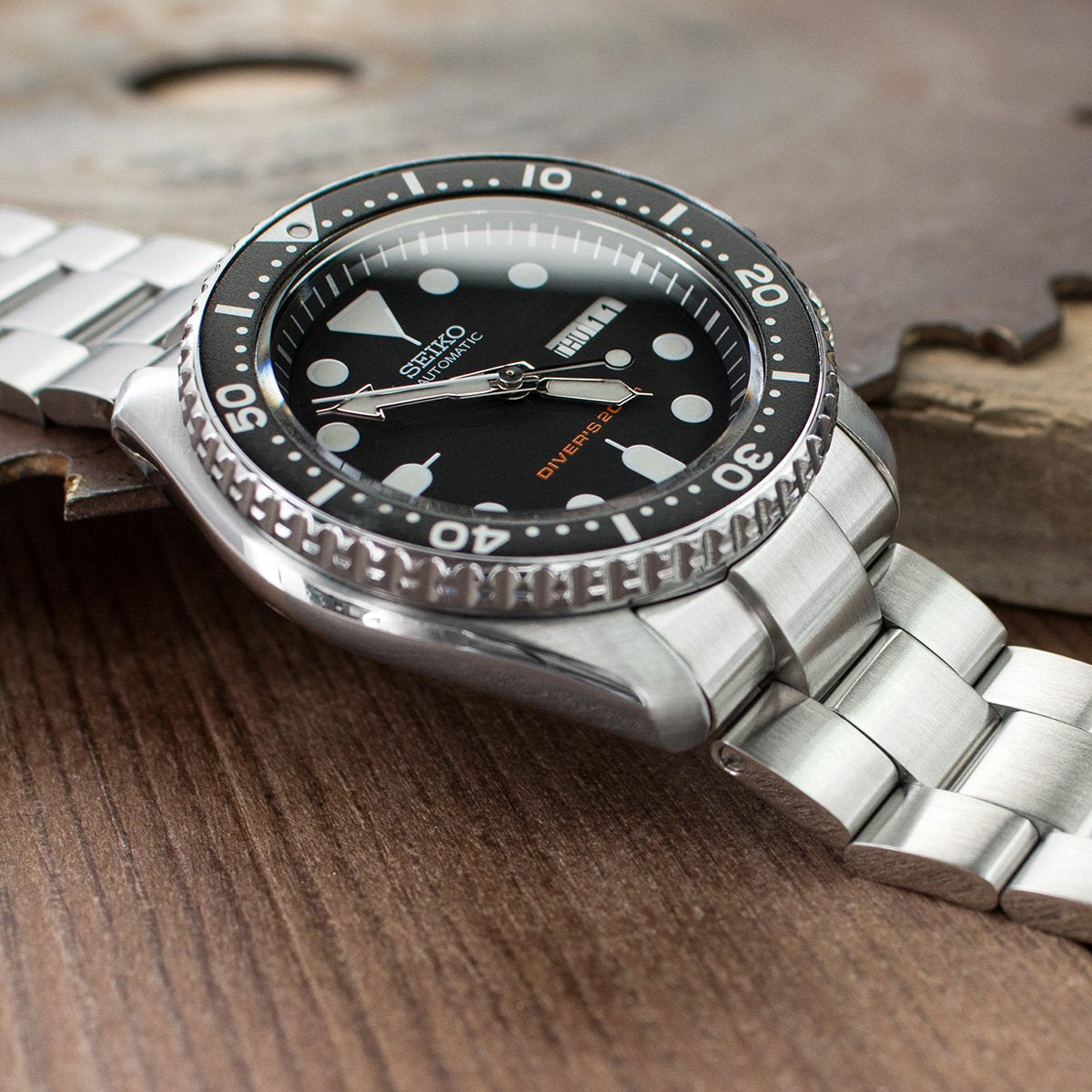 Seiko SKX007 automatic dive watch with stainless steel Super-O Boyer bracelet and black dial on wooden surface
