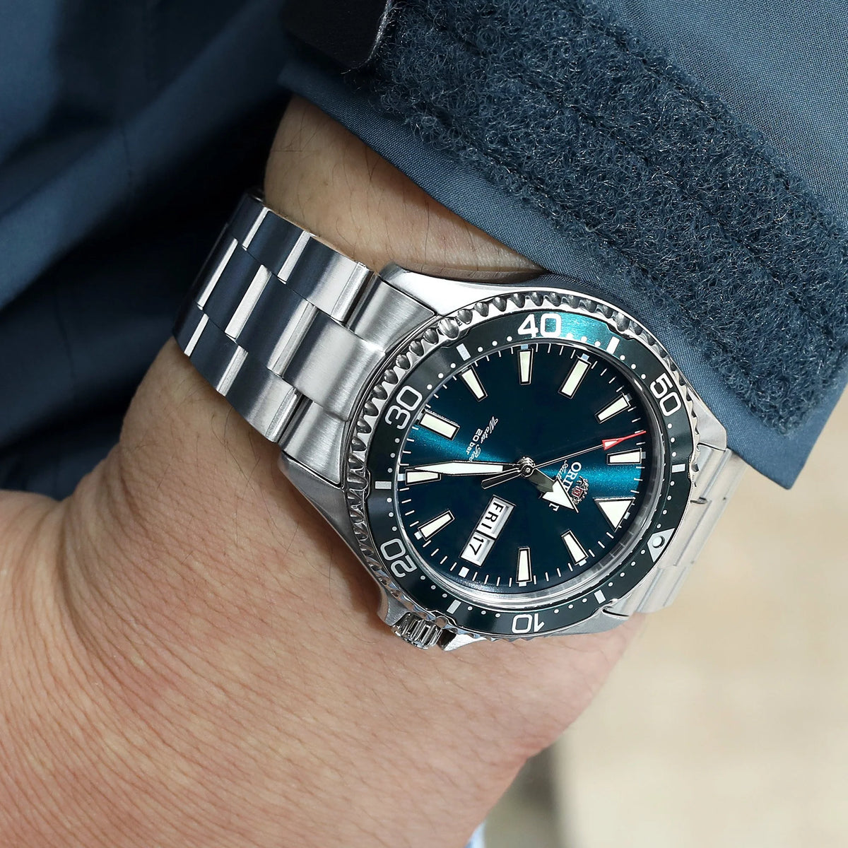 Stainless steel dive watch with Super-O Boyer bracelet on wrist, black dial with date window and turquoise accents