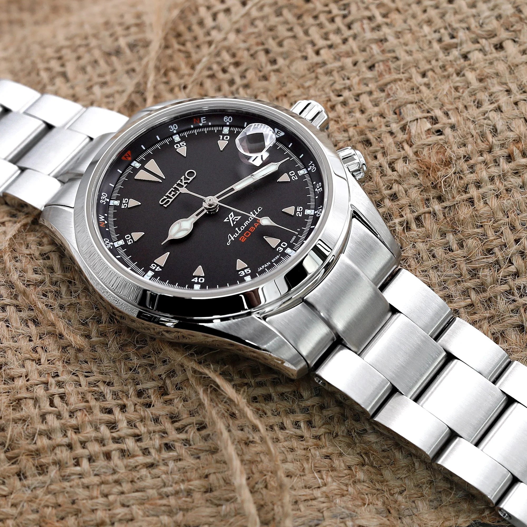 Seiko Alpinist SARB017 watch with stainless steel Super-O Boyer bracelet on textured fabric background