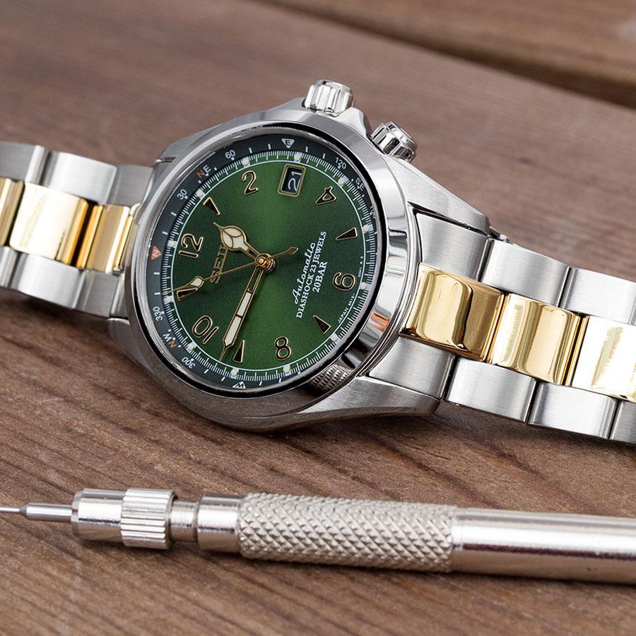Two-tone stainless steel and gold Super-O Boyer bracelet watch with green dial and date window, displayed with spring bar tool