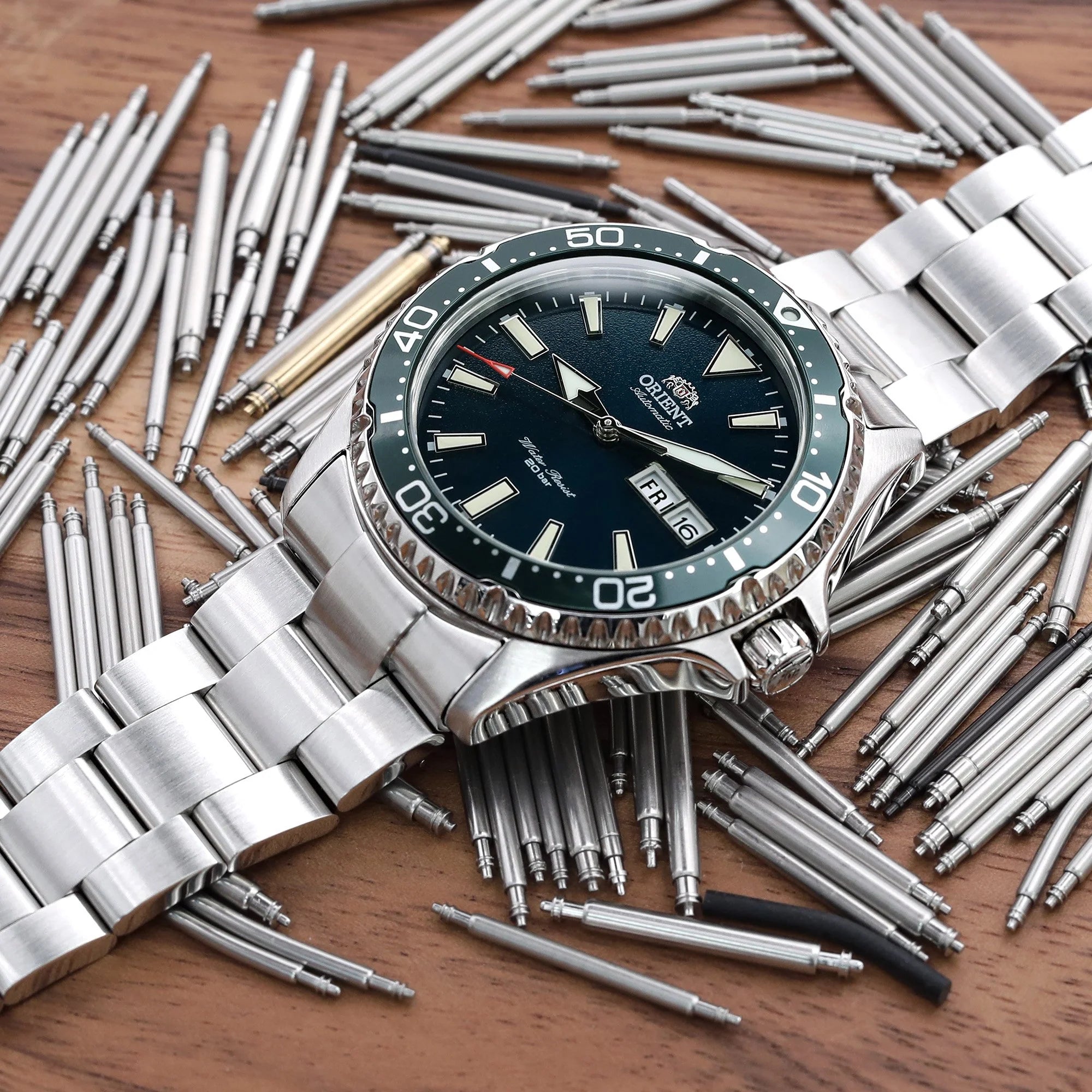 Strapcode Super-O Boyer bracelet on Orient Kamasu dive watch with black dial and steel oyster band surrounded by watchmaking tools