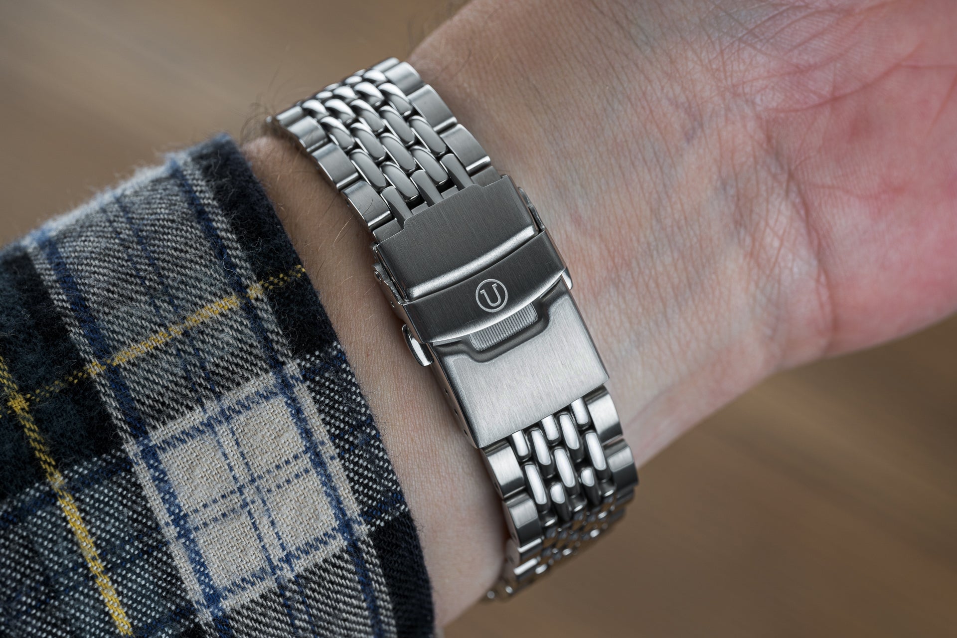 Stainless steel beads of rice watch bracelet with brushed clasp on wrist, paired with tartan fabric sleeve