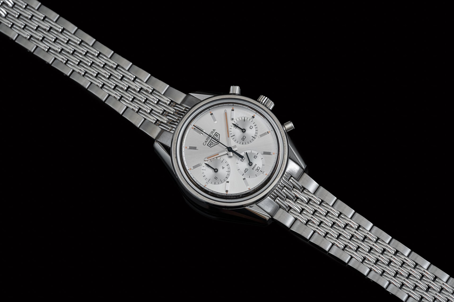Stainless steel chronograph watch with silver dial, subdials, and matching beads of rice bracelet on black background