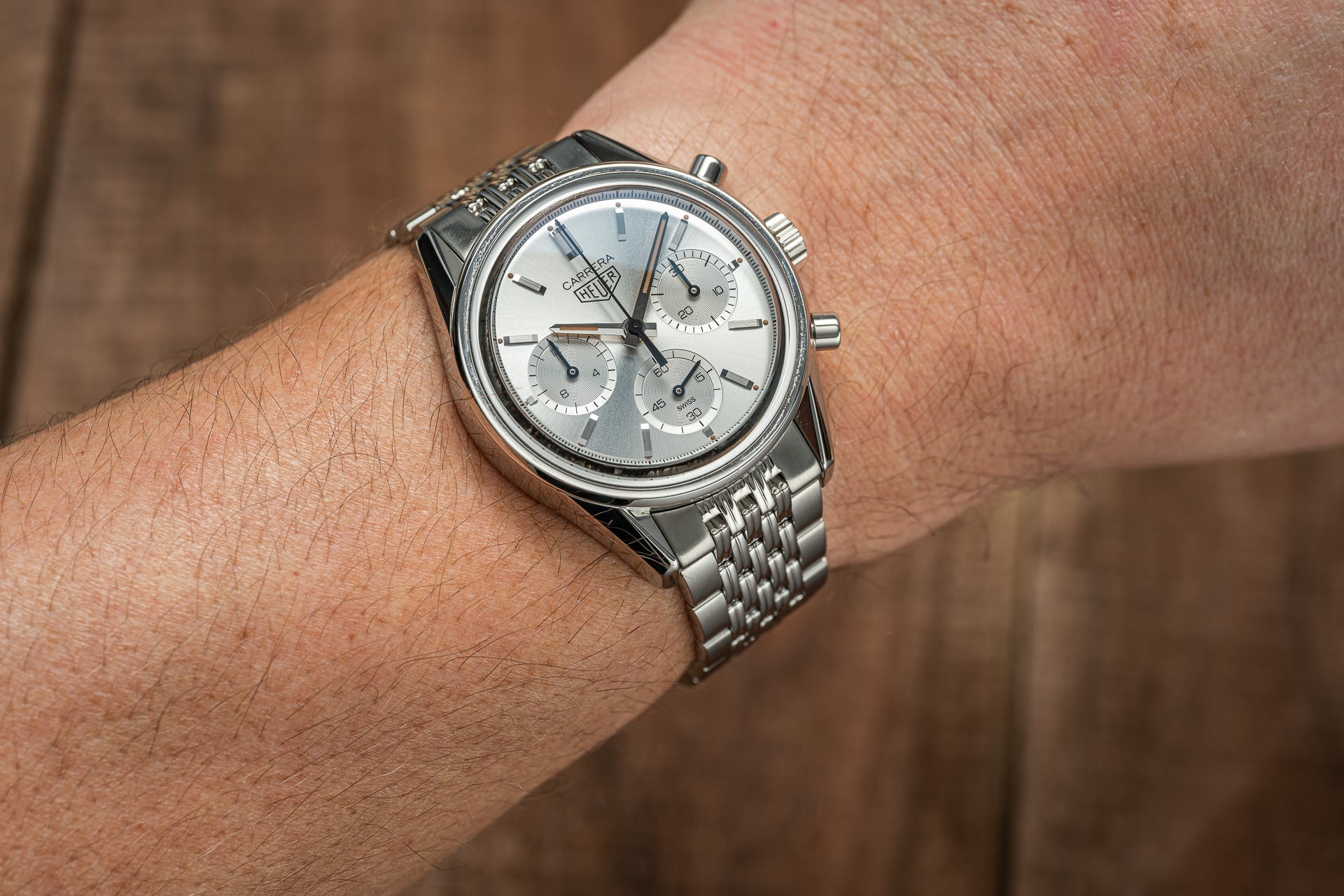 Stainless steel Tag Heuer Carrera chronograph watch with silver dial and subdials on beads of rice bracelet worn on wrist