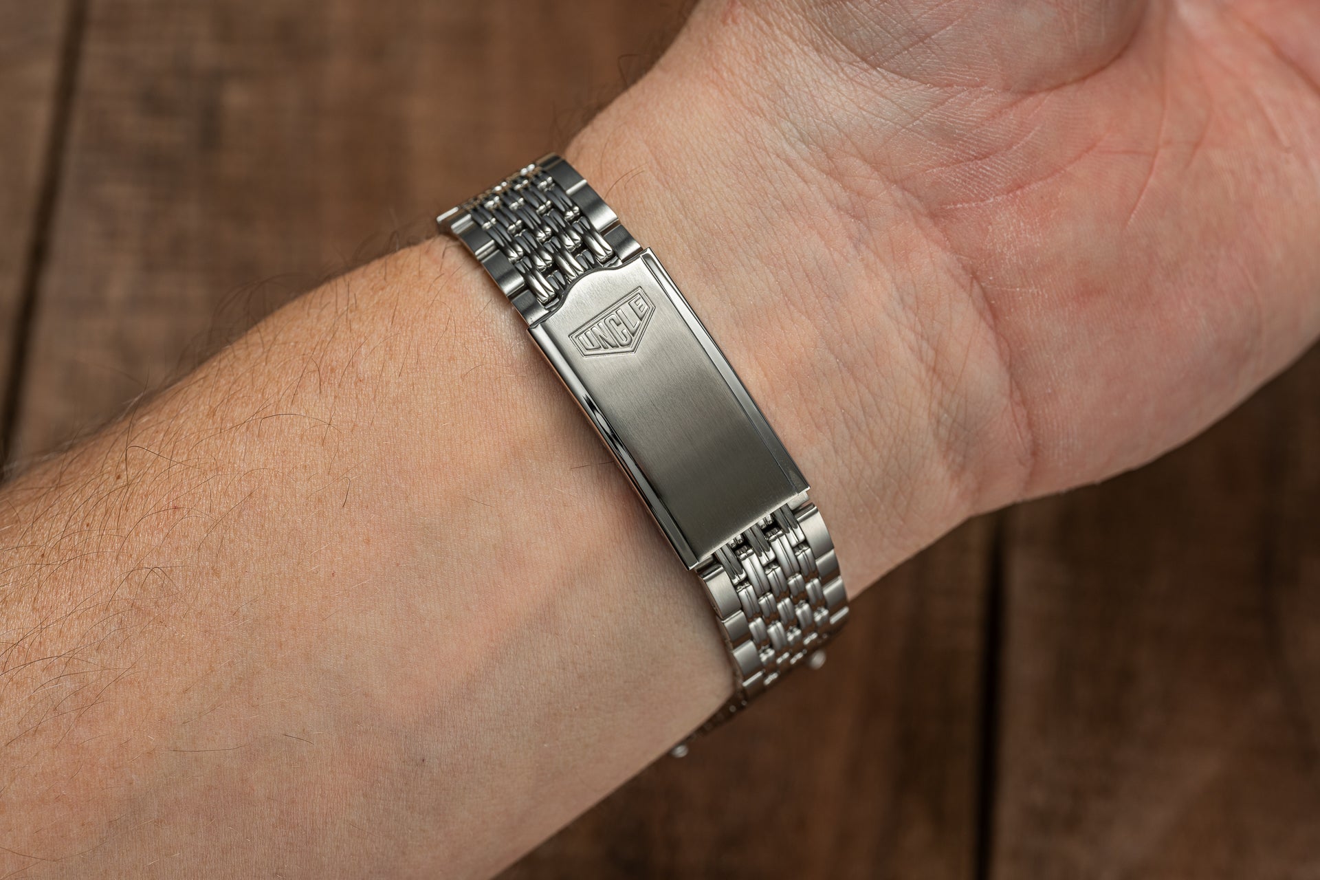 Stainless steel beads of rice bracelet with engrossed tag shield on man's wrist