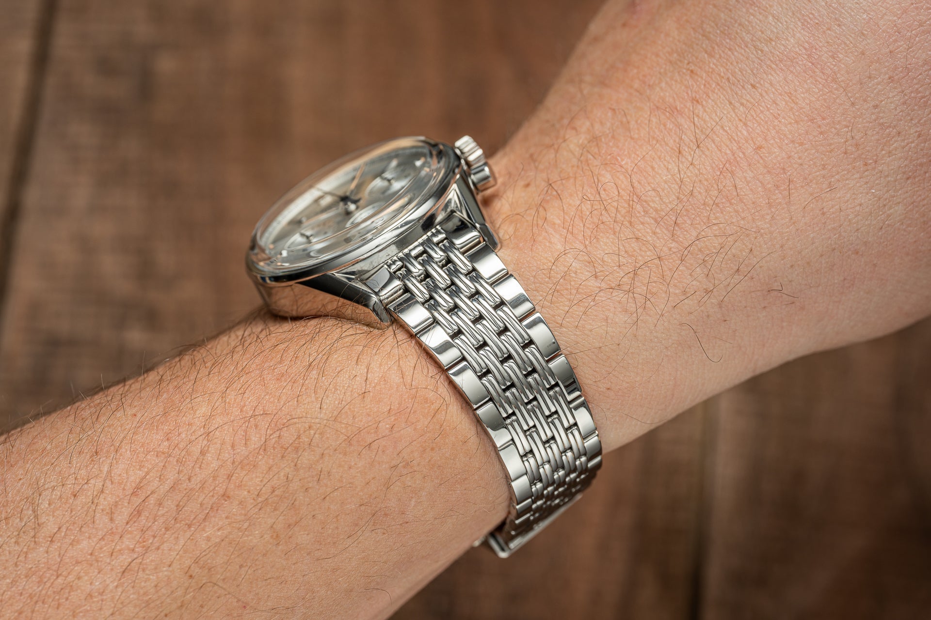 Silver stainless steel watch with beads of rice bracelet worn on wrist, featuring round white dial and polished metal band
