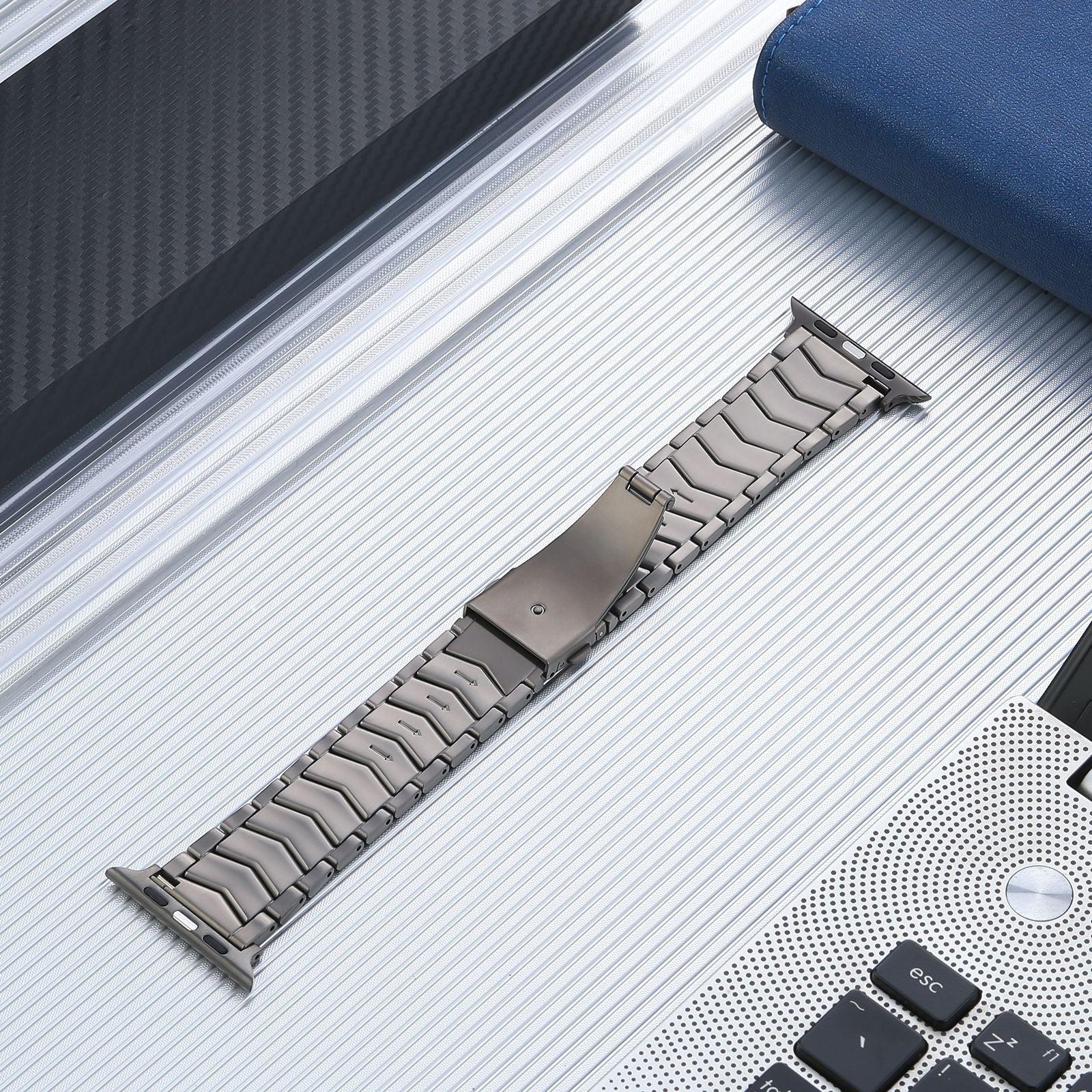 Titanium arched bracelet for Apple Watch with polished metal links and adjustable clasp on striped surface