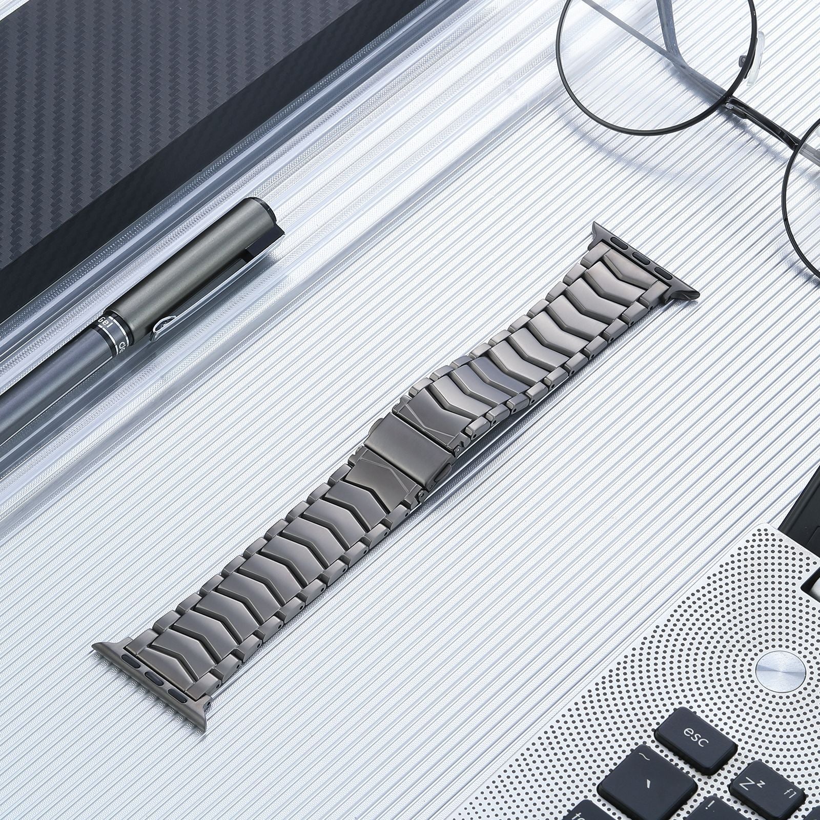 Titanium arched bracelet band for Apple Watch with curved links, displayed on white lined surface with accessories