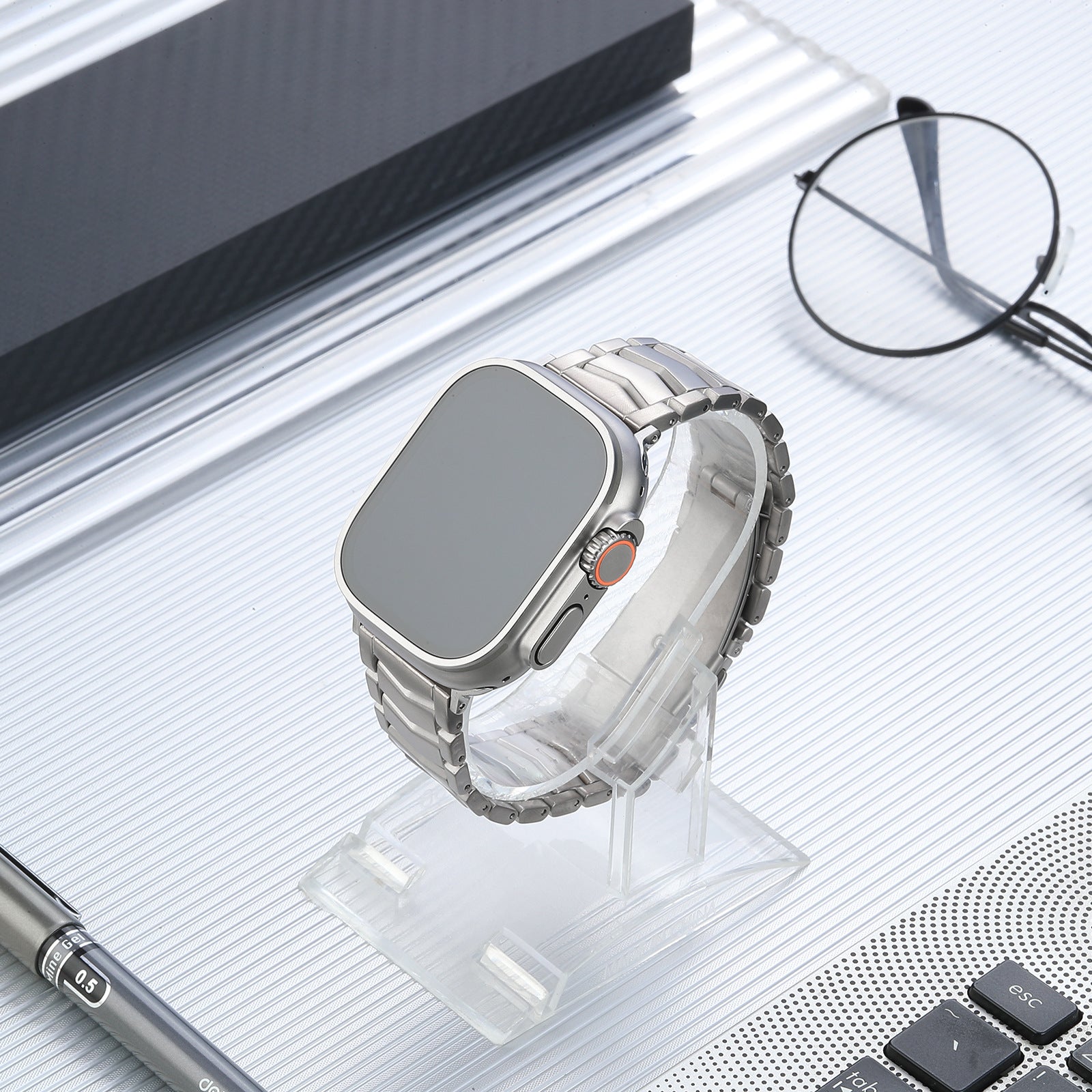 Silver titanium smartwatch with arched bracelet band on clear display stand, modern minimalist product photography