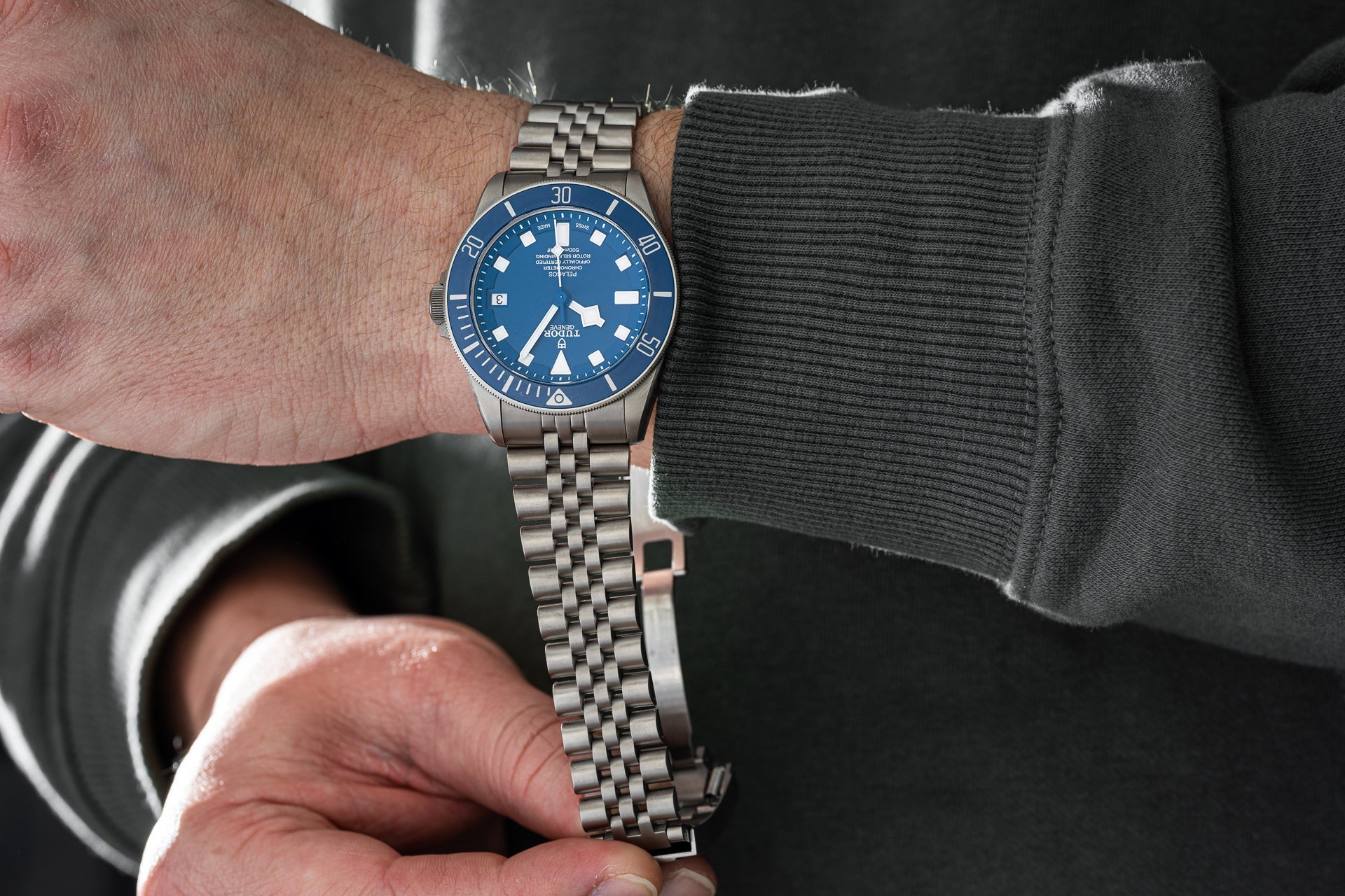 Stainless steel bracelet with jubilee links and secure clasp fitted on blue dial dive watch worn on wrist