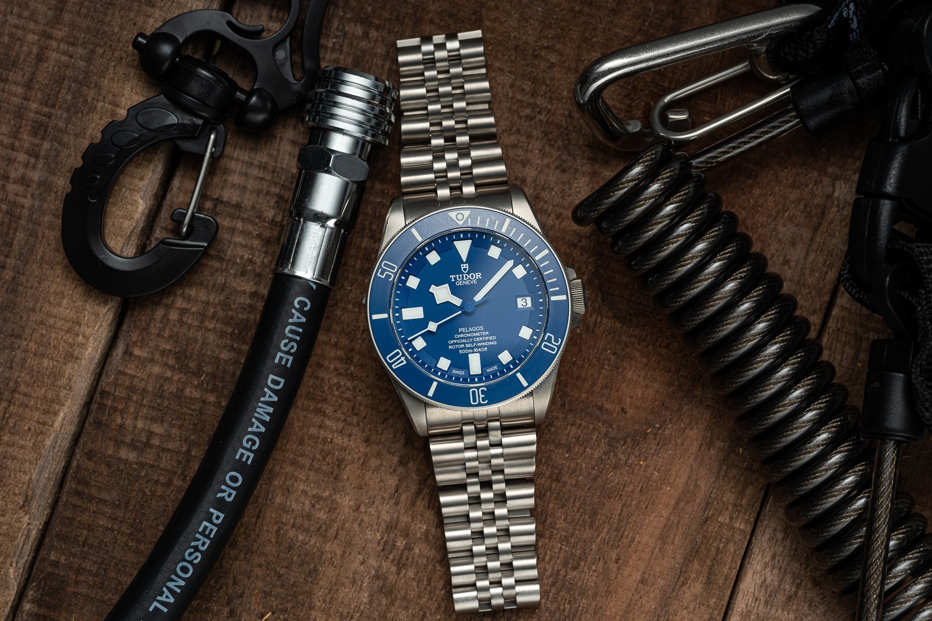 Titanium executive bracelet with secure clasp designed for Tudor Pelagos 42mm watch, displayed with tactical gear on brown fabric