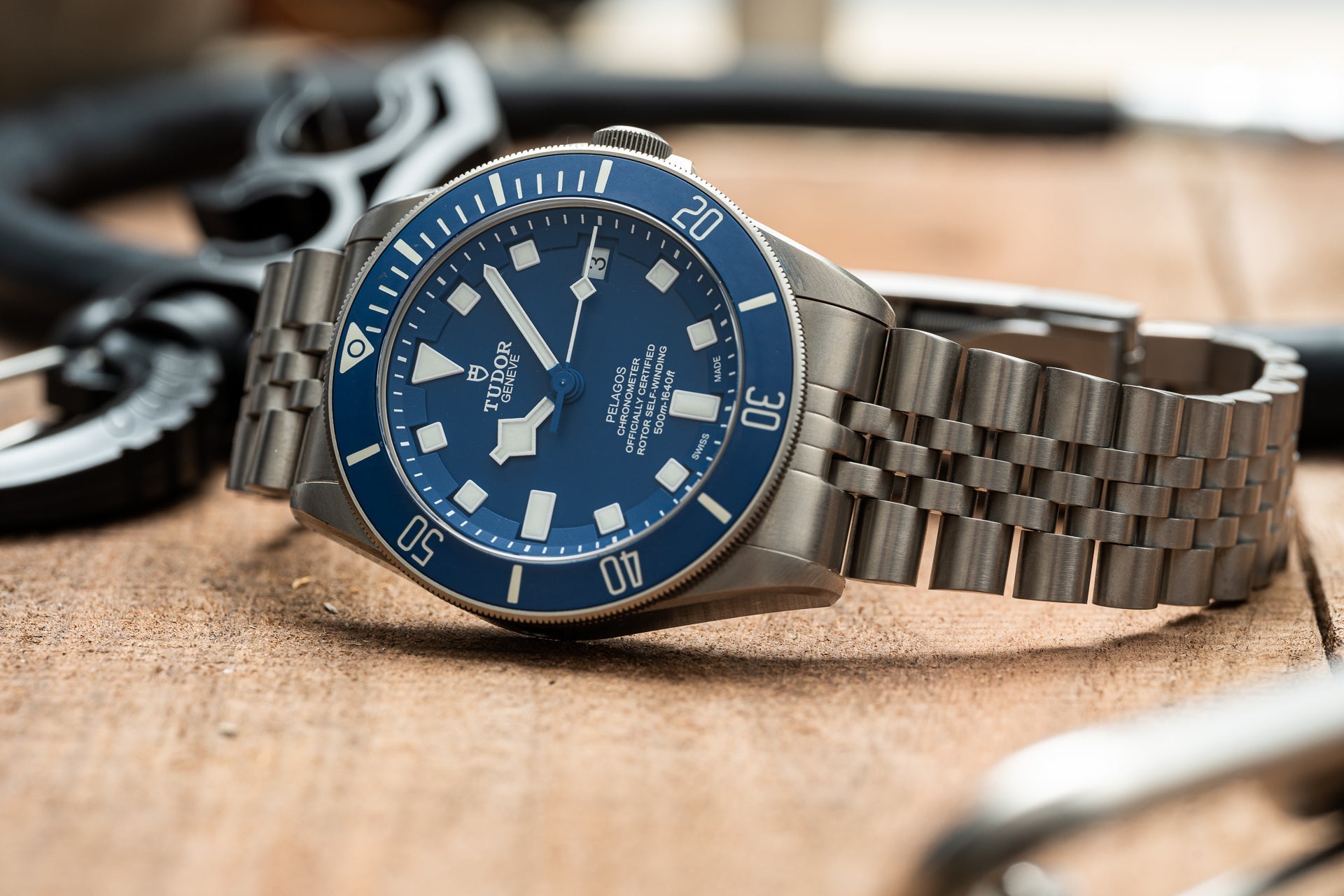 Tudor Pelagos 42mm titanium dive watch with blue dial and steel bracelet on sandy surface