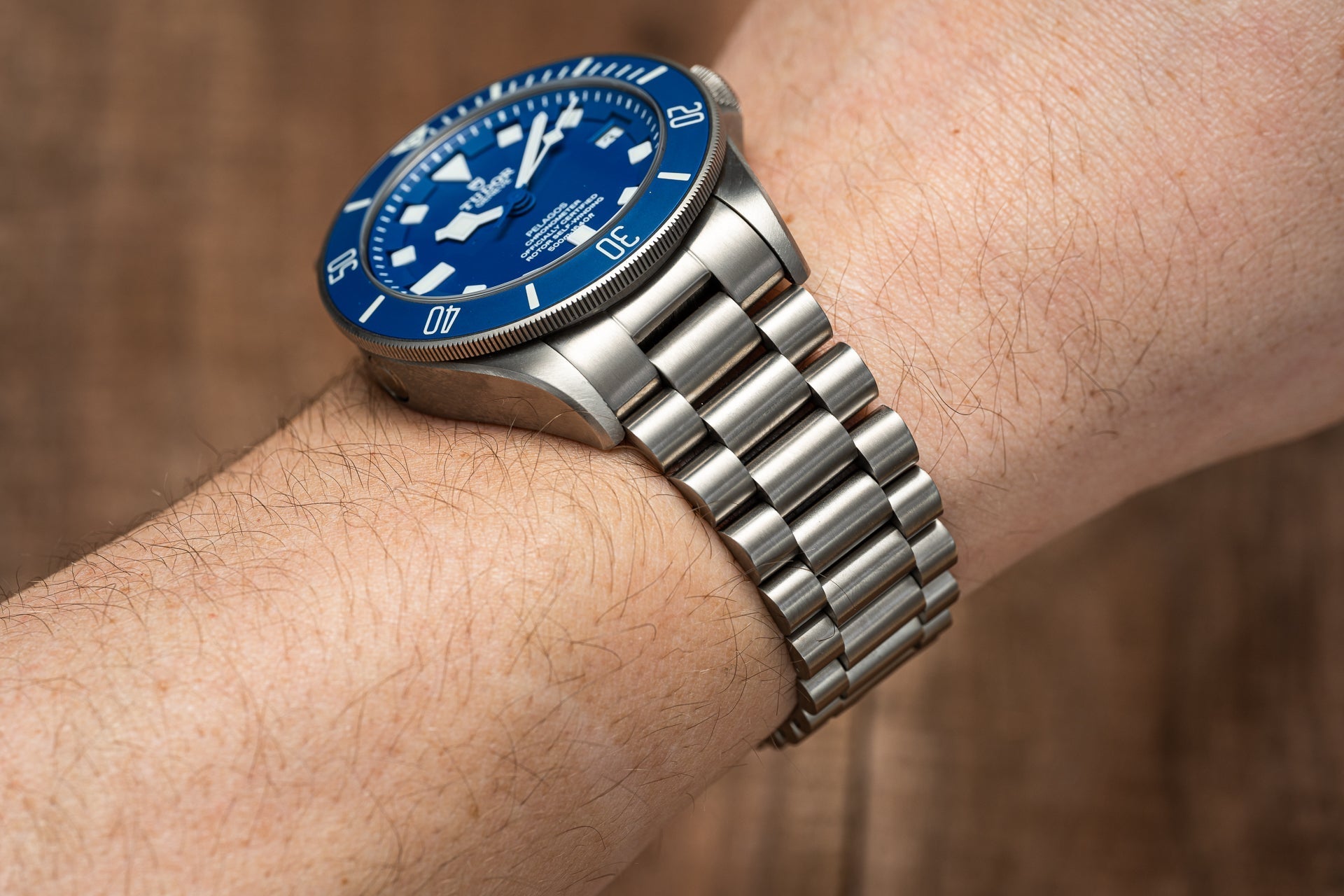 Men's dive watch with blue dial and rotating bezel on stainless steel bracelet worn on wrist, showing clasp and link details