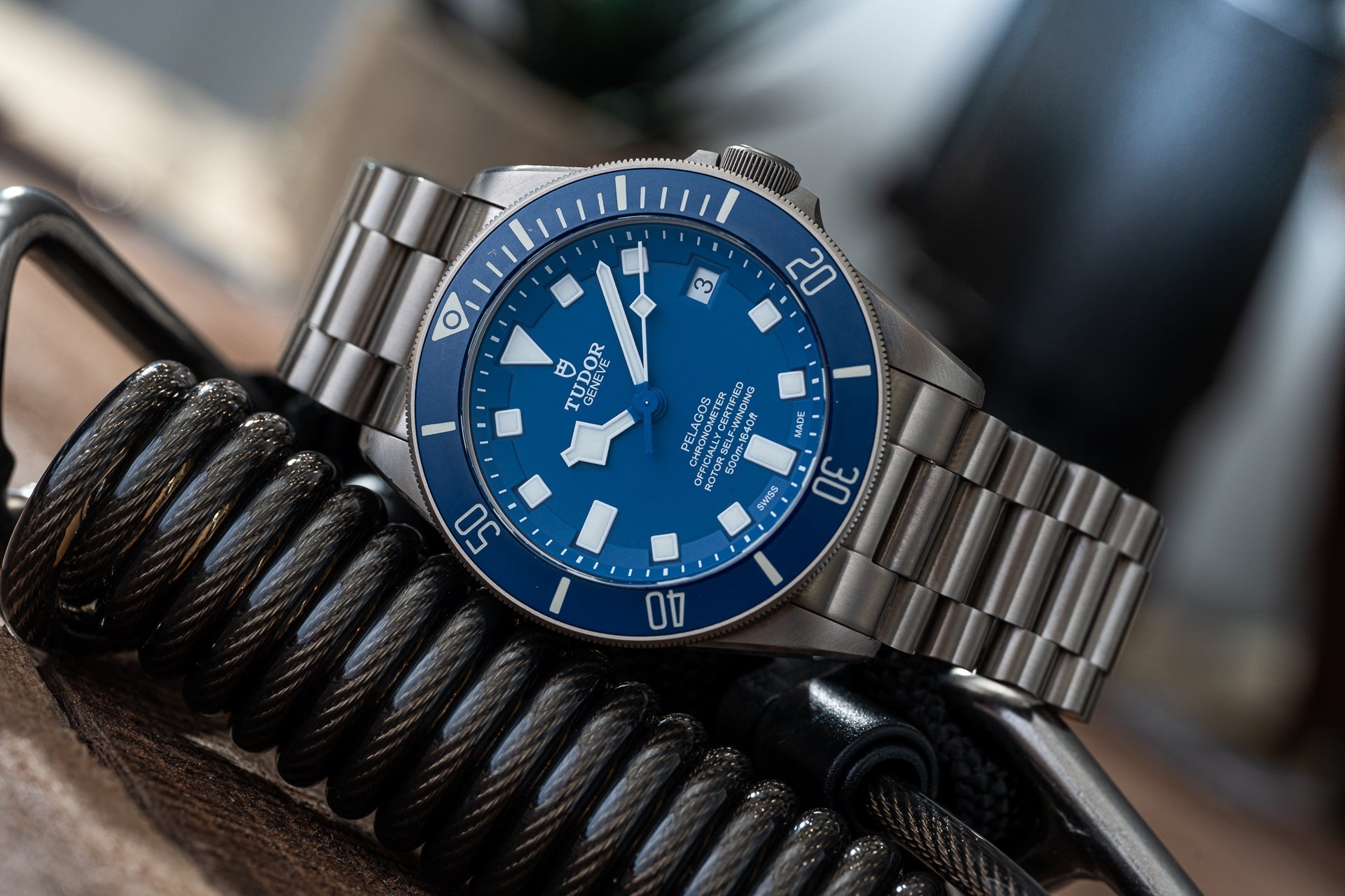 Stainless steel dive watch with blue dial and bezel on matching metal bracelet with tactical rope