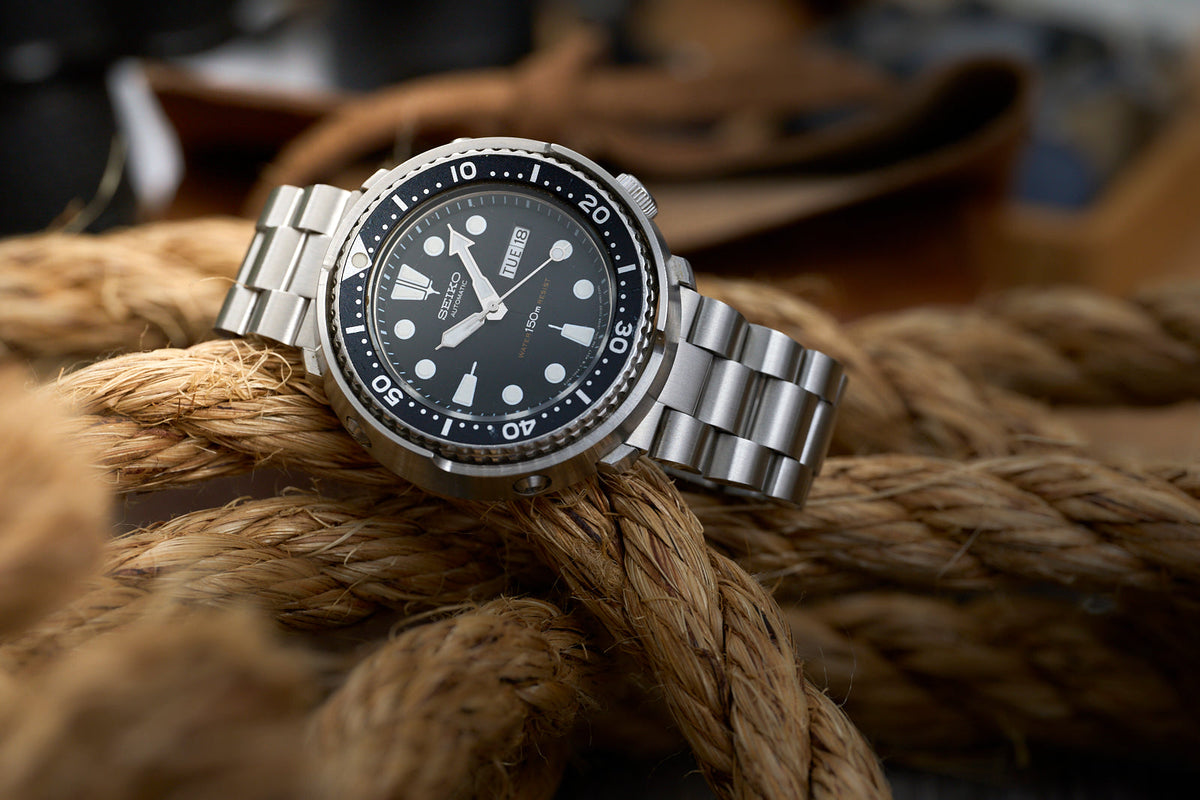 Seiko Prospex dive watch with black dial and stainless steel bracelet on natural rope background