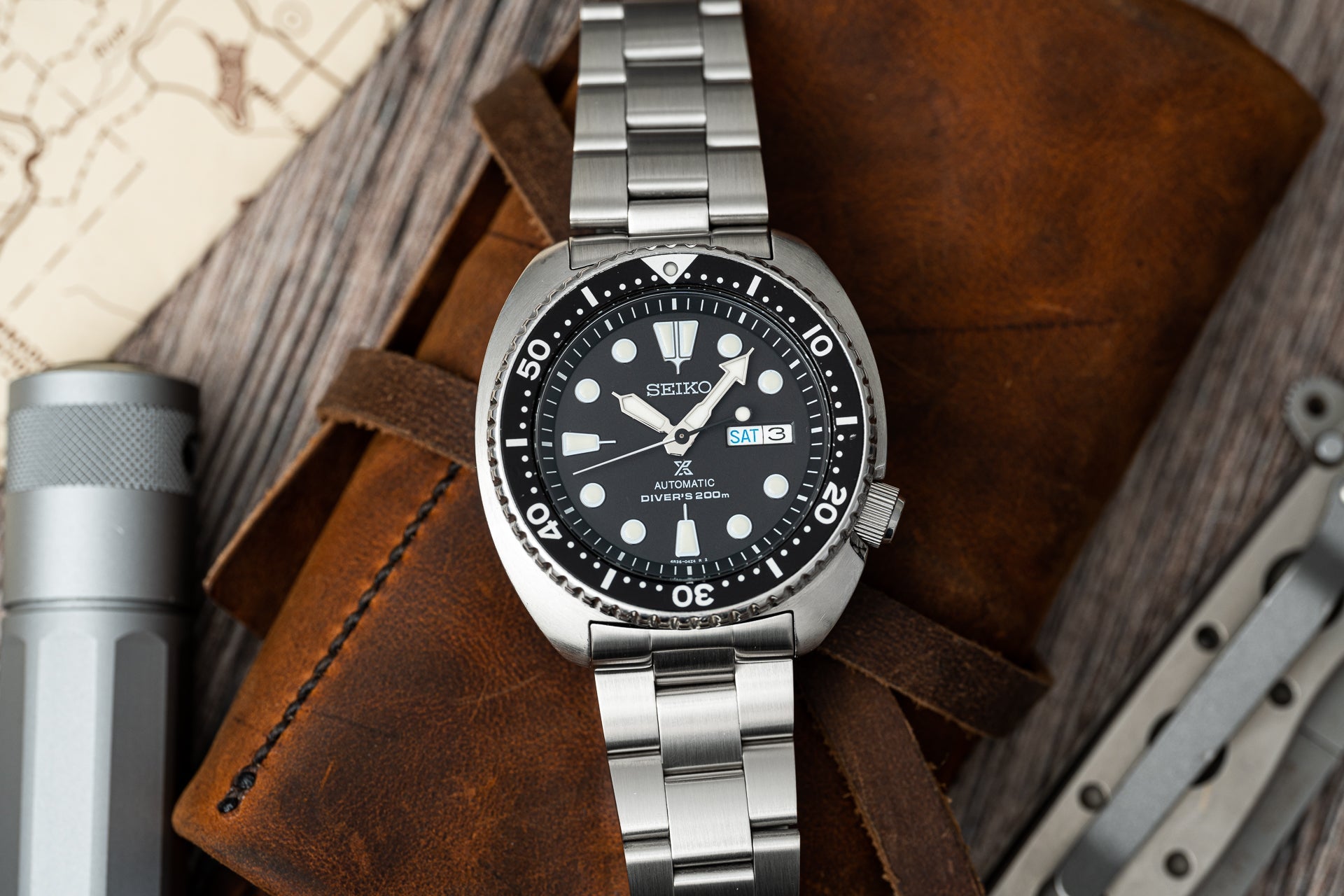Seiko automatic diver's watch with black dial, stainless steel bracelet, and 200m water resistance on brown leather