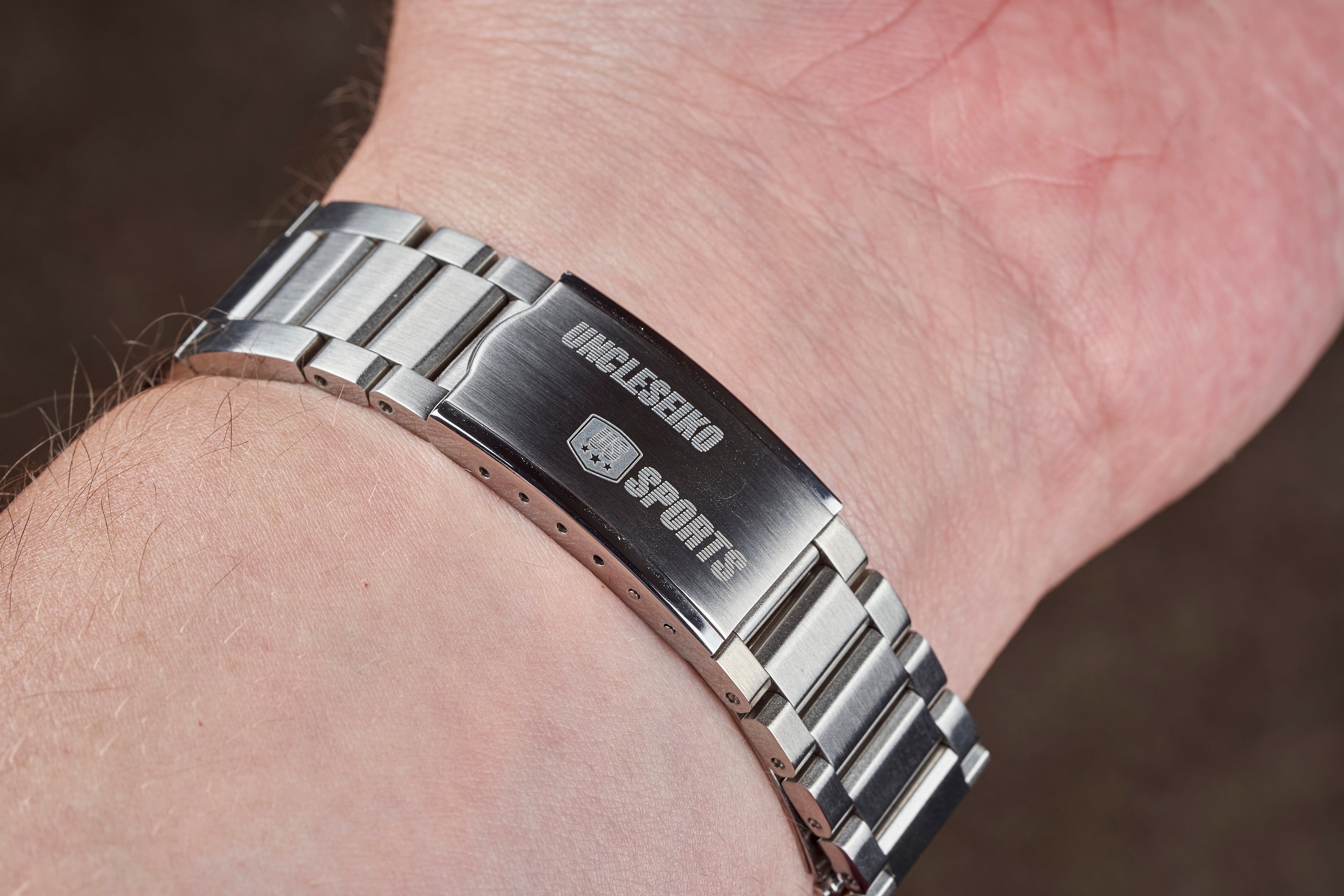 Stainless steel tapered bracelet with brushed center link and polished outer links, featuring deployant clasp on wrist