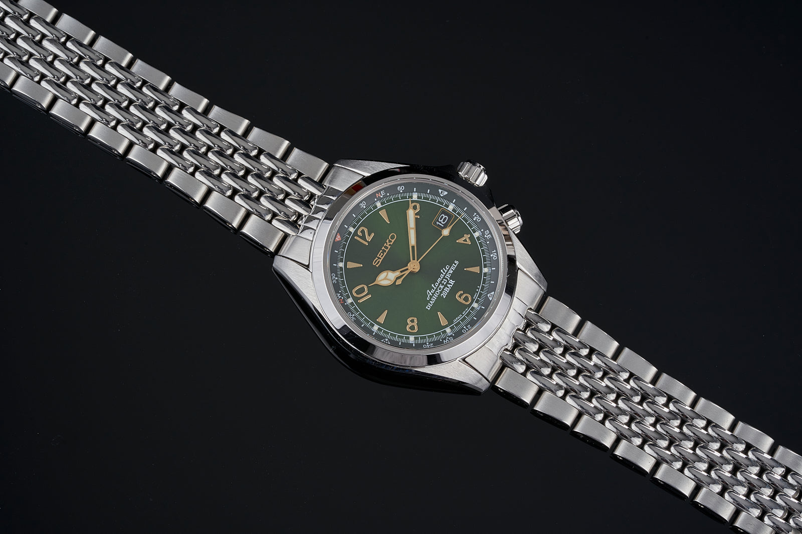 Seiko Prospex Alpinist SARB017 automatic watch with green dial, gold numerals, and stainless steel bracelet on black background