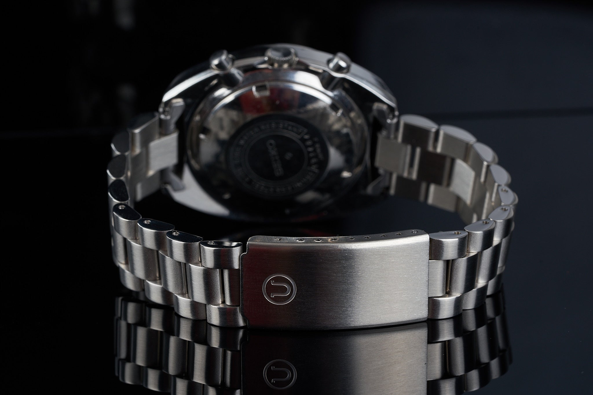 Stainless steel chronograph watch with linked metal bracelet and fold-over clasp displayed against dark background