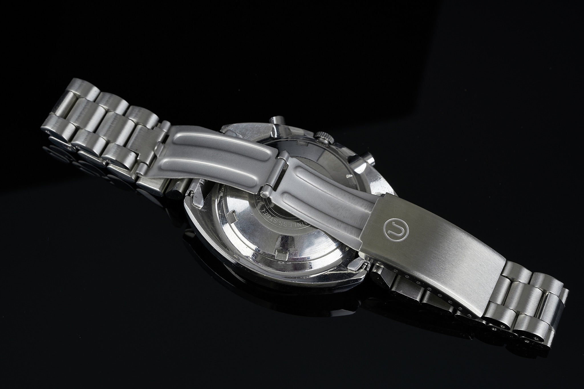 Stainless steel chronograph watch with metal bracelet featuring rounded case design and exposed pushers on black background