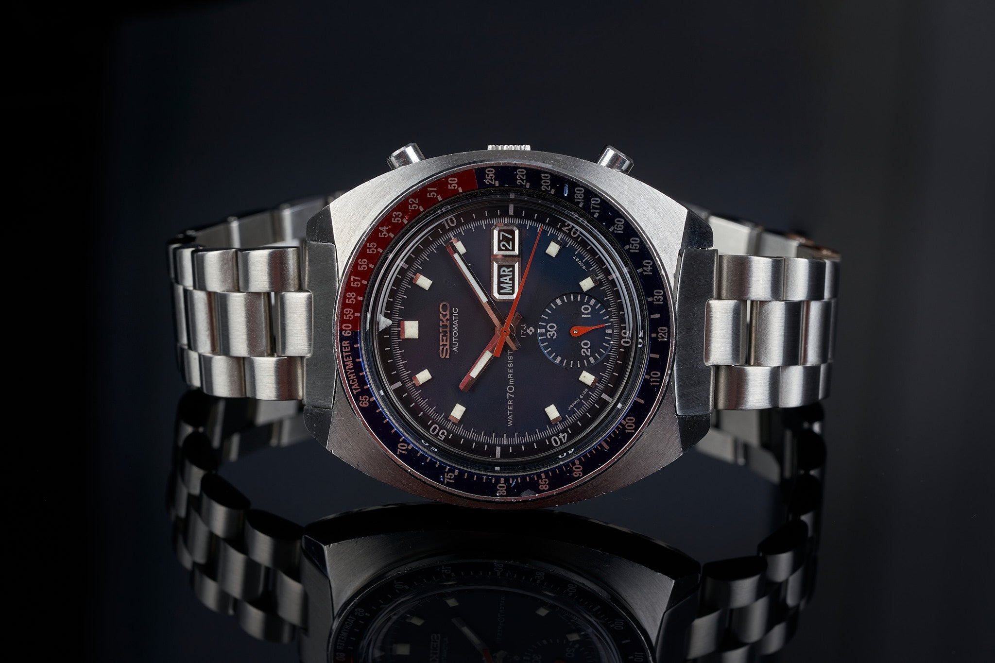 Vintage Seiko 6139 chronograph watch with stainless steel bracelet, black dial, red accents and day-date window