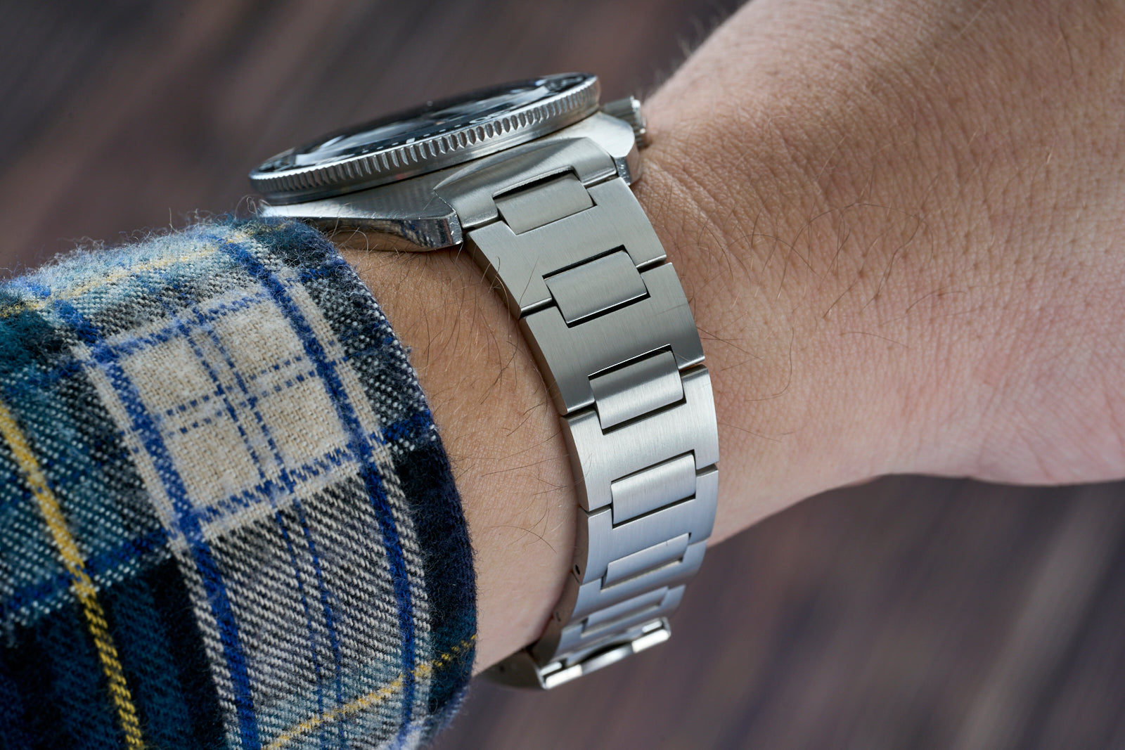 Stainless steel H-Link bracelet for Seiko 6105 watch worn on wrist with plaid shirt sleeve