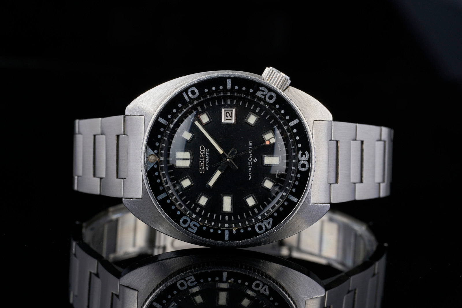 Vintage Seiko 6105 automatic dive watch with black dial, luminous square indices, stainless steel H-Link bracelet, date window, and rotating bezel on black background