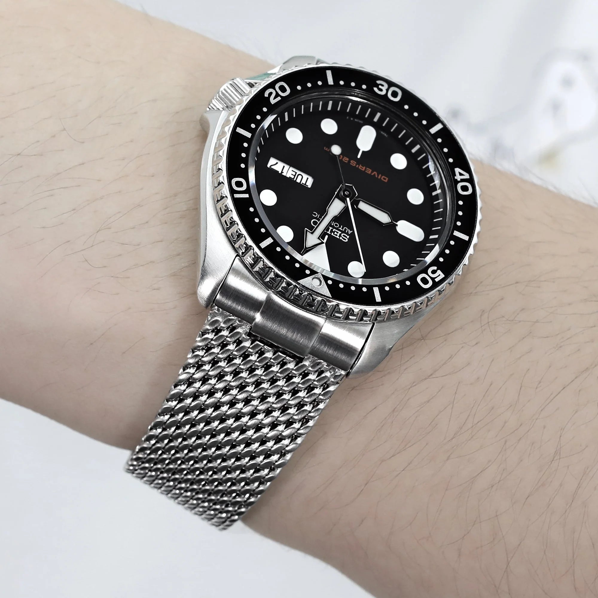 Seiko SKX007 dive watch with stainless steel mesh bracelet on wrist, black dial with luminous dot markers