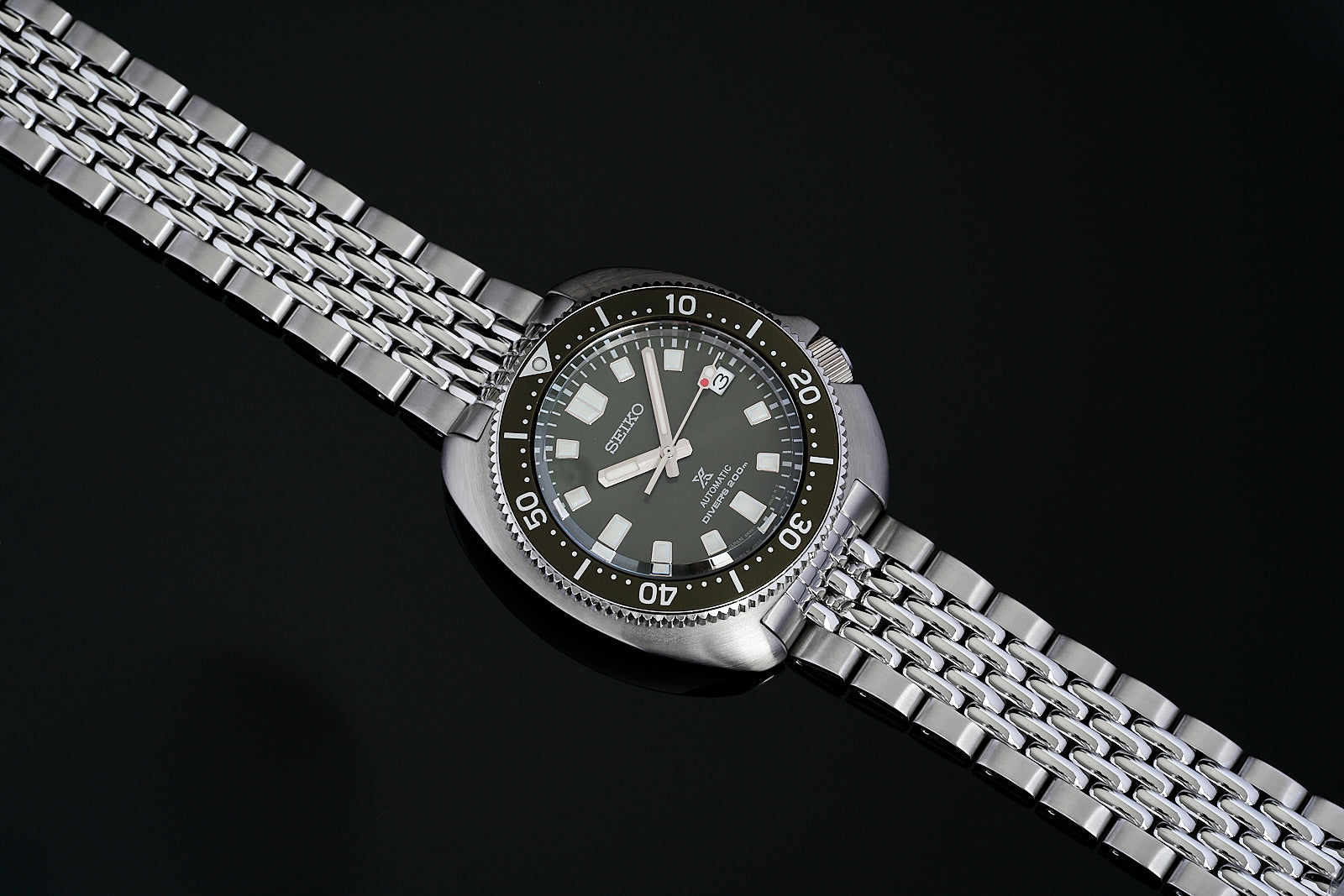 Seiko Prospex diver watch with stainless steel beads of rice bracelet, black dial, and rotating bezel on black background
