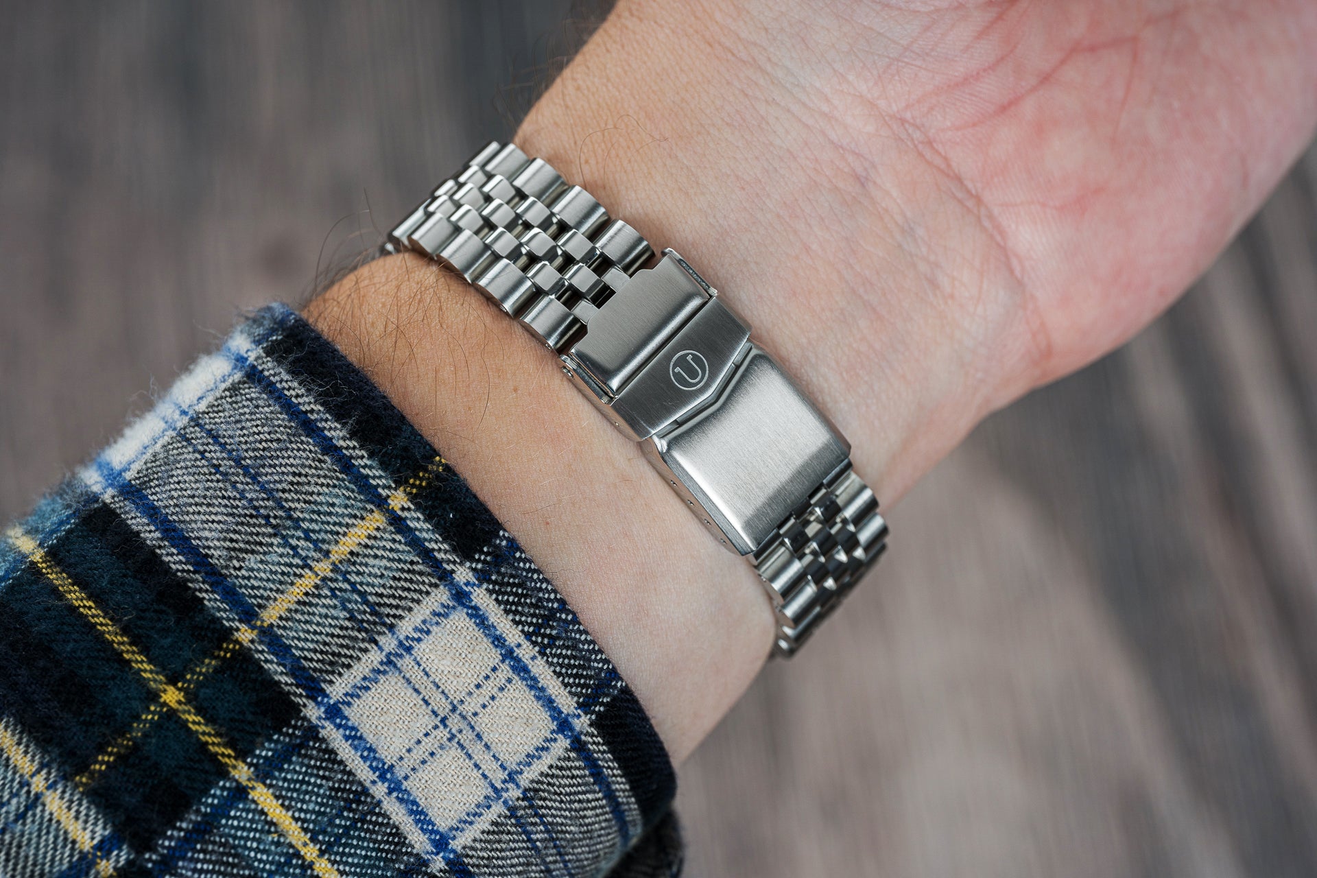 Stainless steel Seiko Willard dive watch with metal bracelet worn on wrist with plaid sleeve