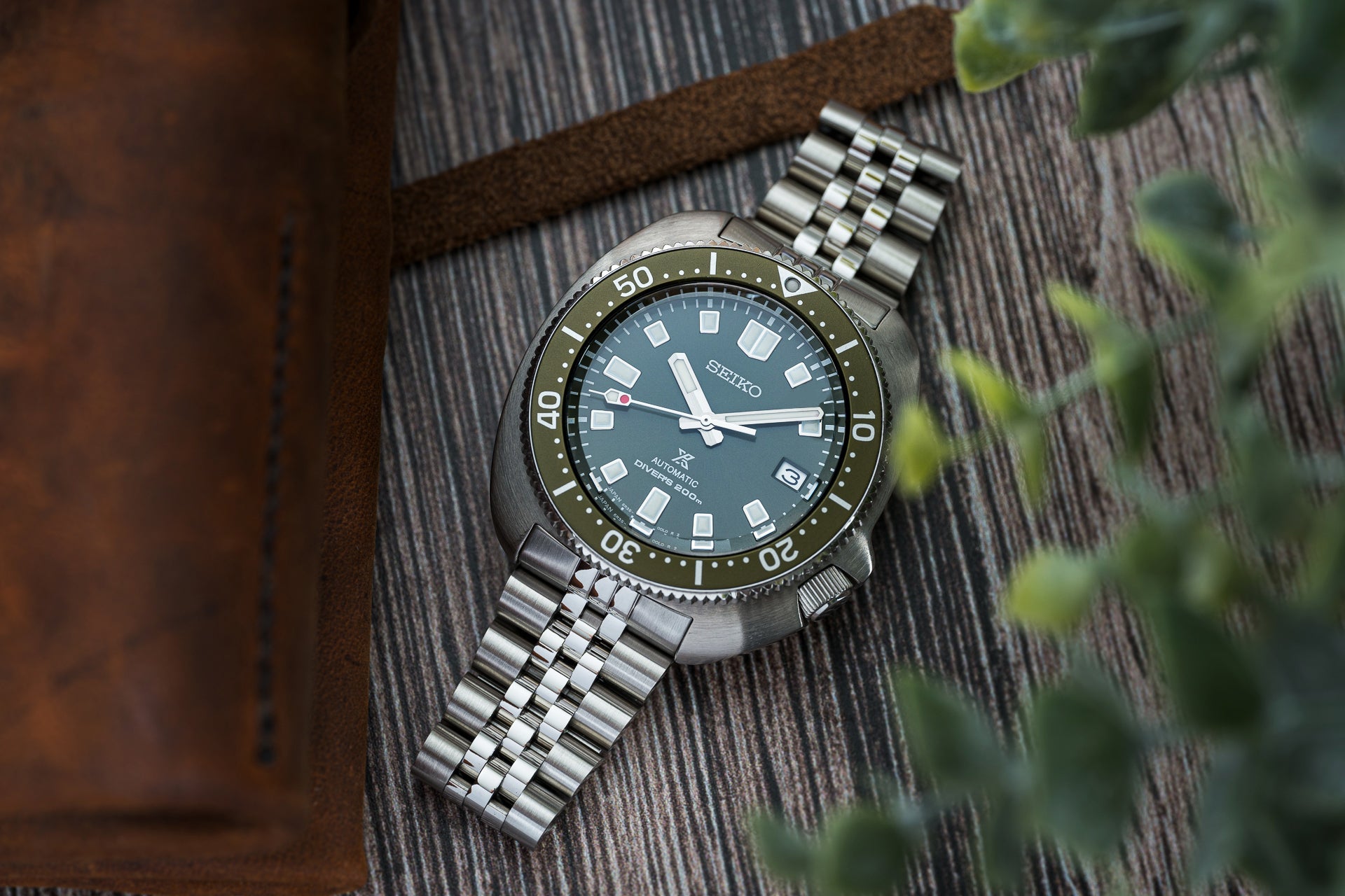 Seiko Prospex SPB151 automatic dive watch with green dial, stainless steel bracelet, and rotating bezel on textured surface