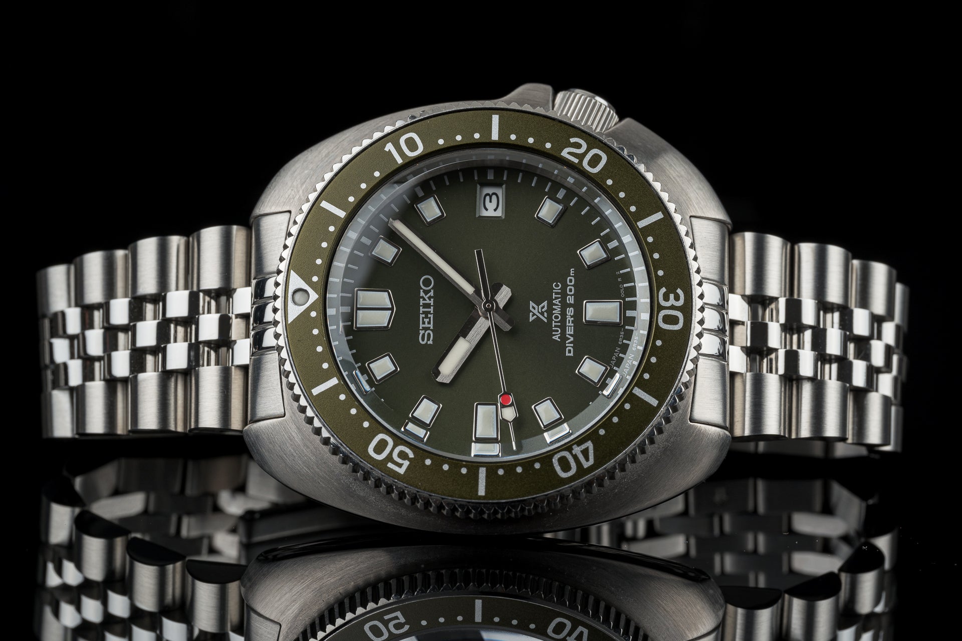 Seiko SPB15x Willard automatic diver watch with olive dial, steel bracelet, and rotating bezel on black background