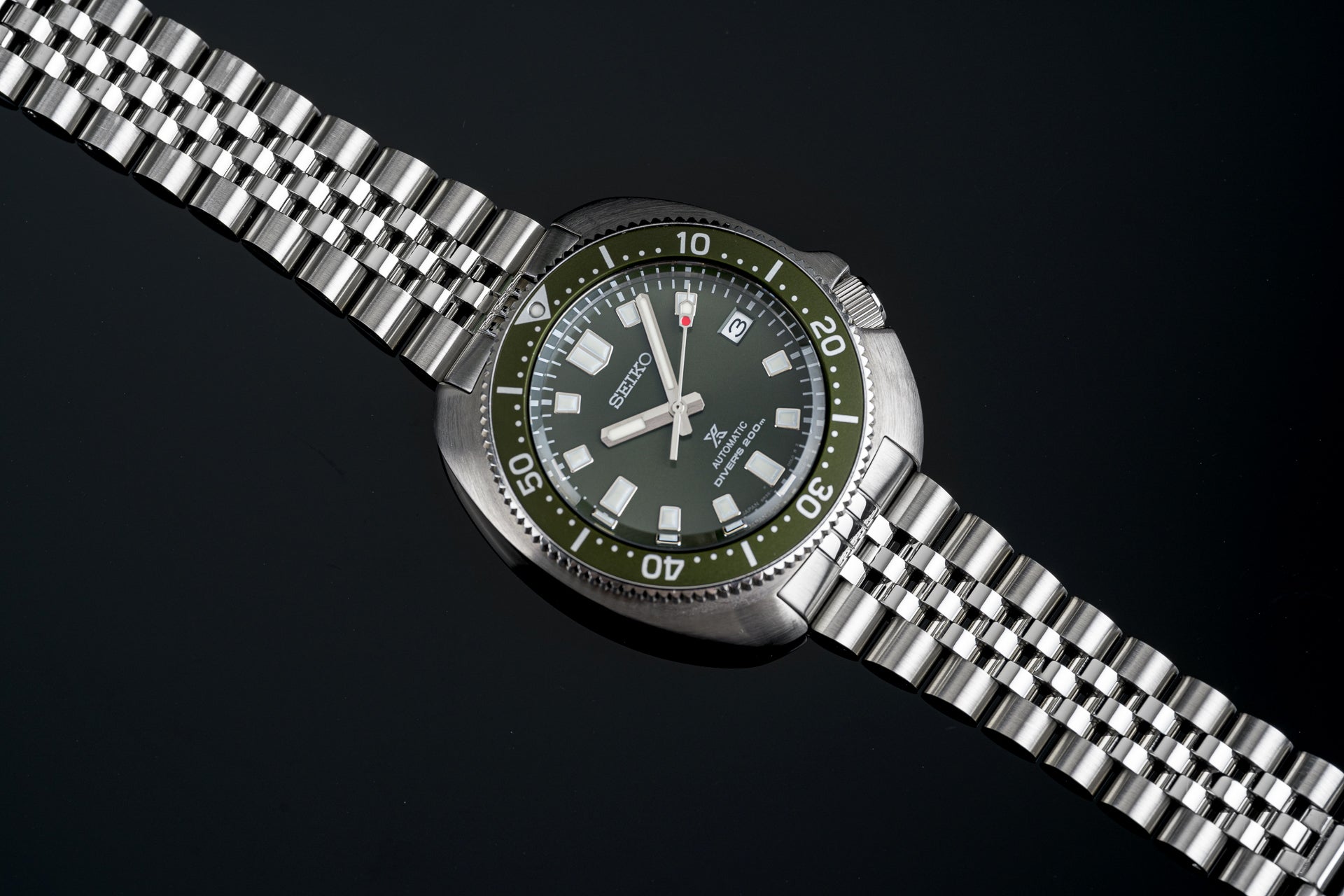 Seiko SPB15x Willard automatic dive watch with olive green dial, stainless steel bracelet and rotating bezel on black background