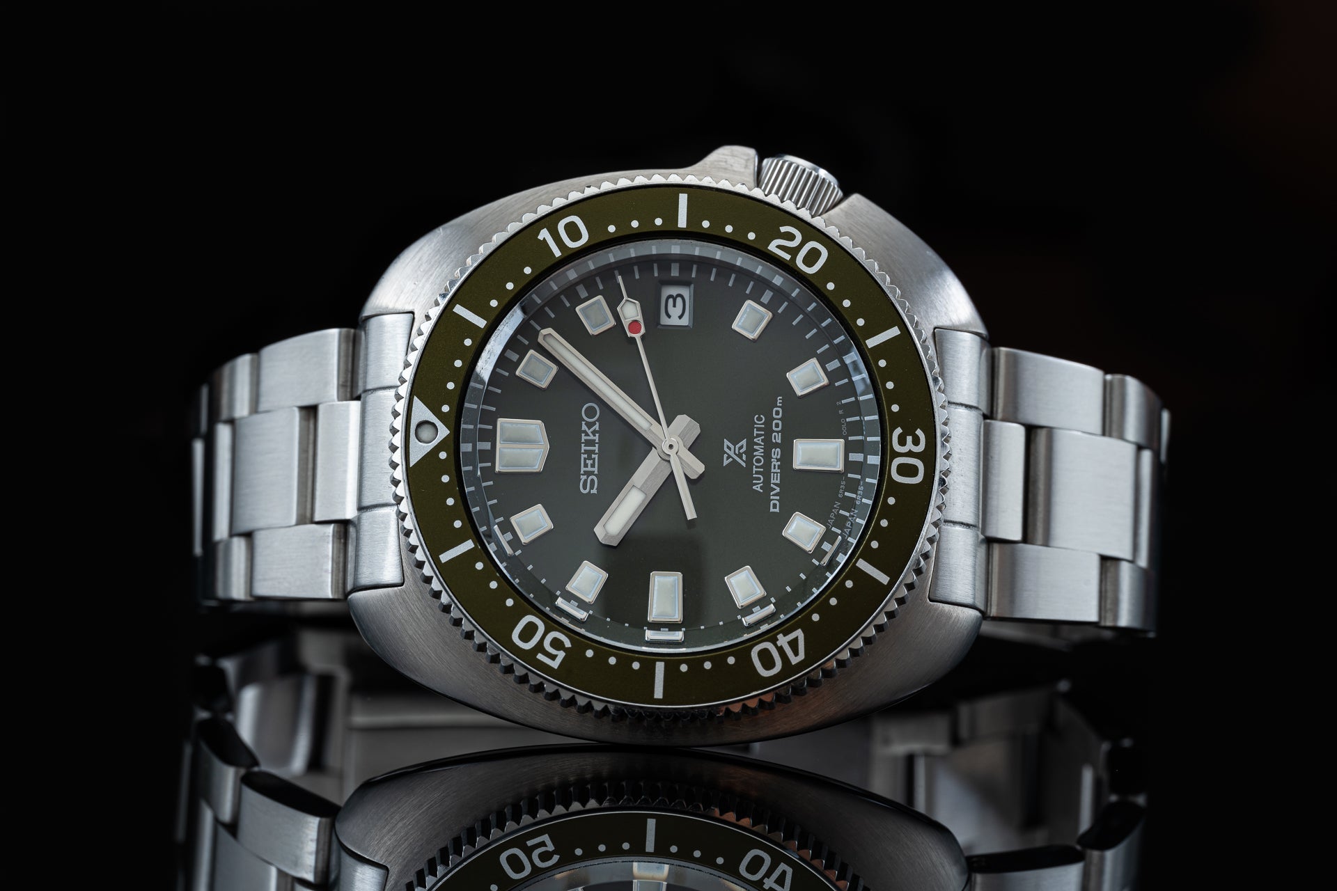 Seiko Prospex Willard automatic diver watch with olive bezel, steel bracelet, and dark dial against black background