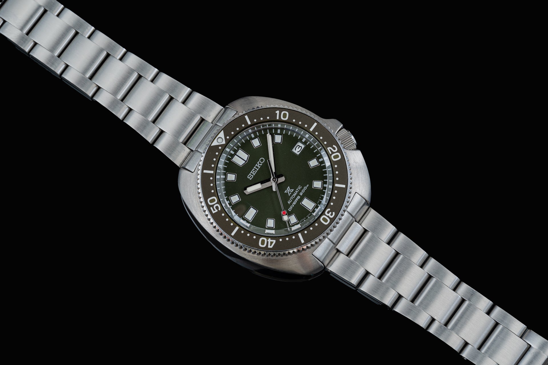 Seiko Prospex Willard dive watch with olive green dial, stainless steel bracelet, rotating bezel, and date window on black background