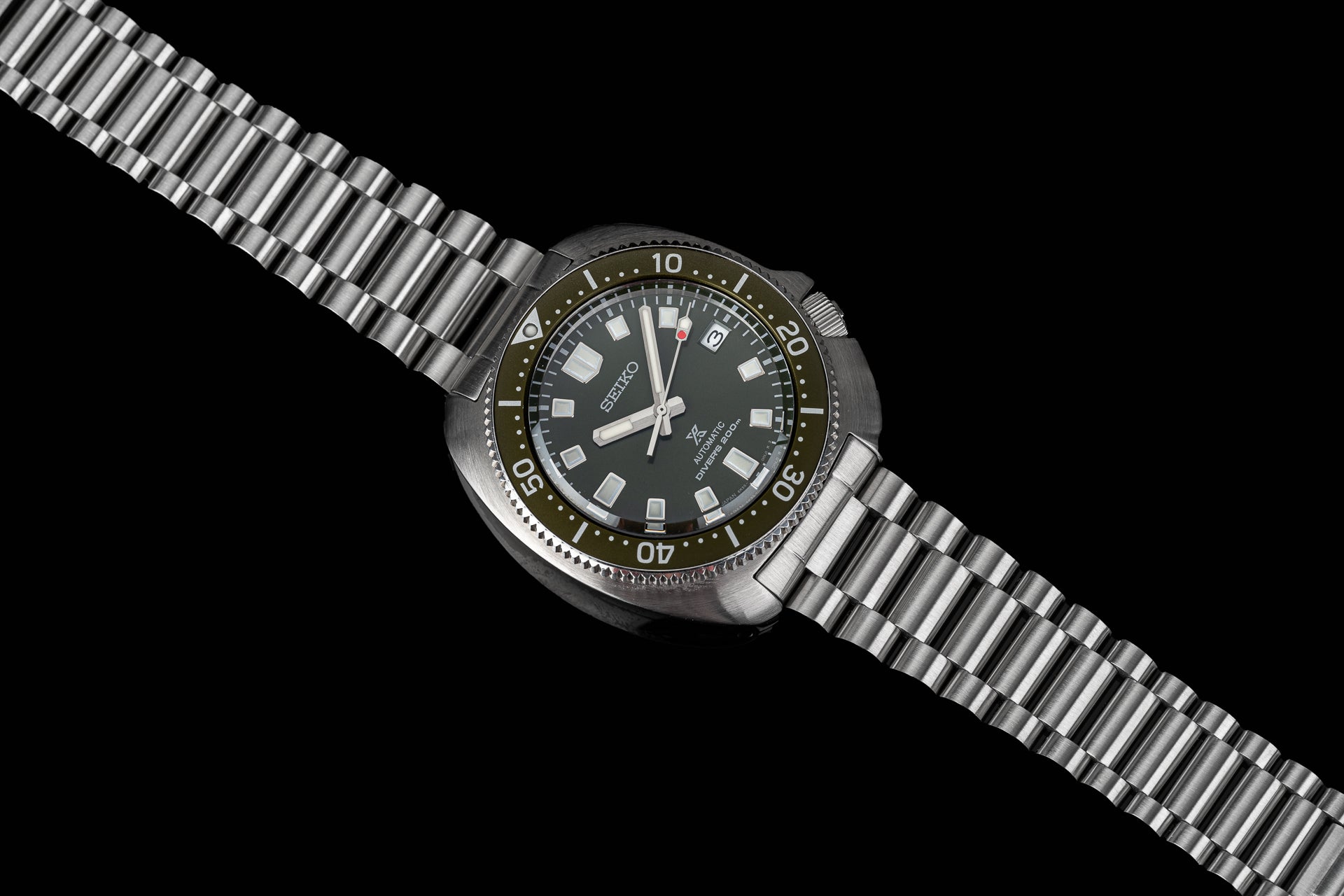 Seiko Prospex automatic dive watch with dark dial, luminous hands, date window, rotating bezel, and stainless steel bracelet on black background