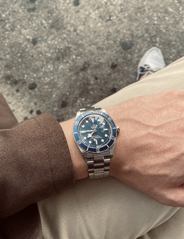 Stainless steel Super-O Boyer bracelet on Tudor Black Bay 58 watch worn on wrist against concrete background