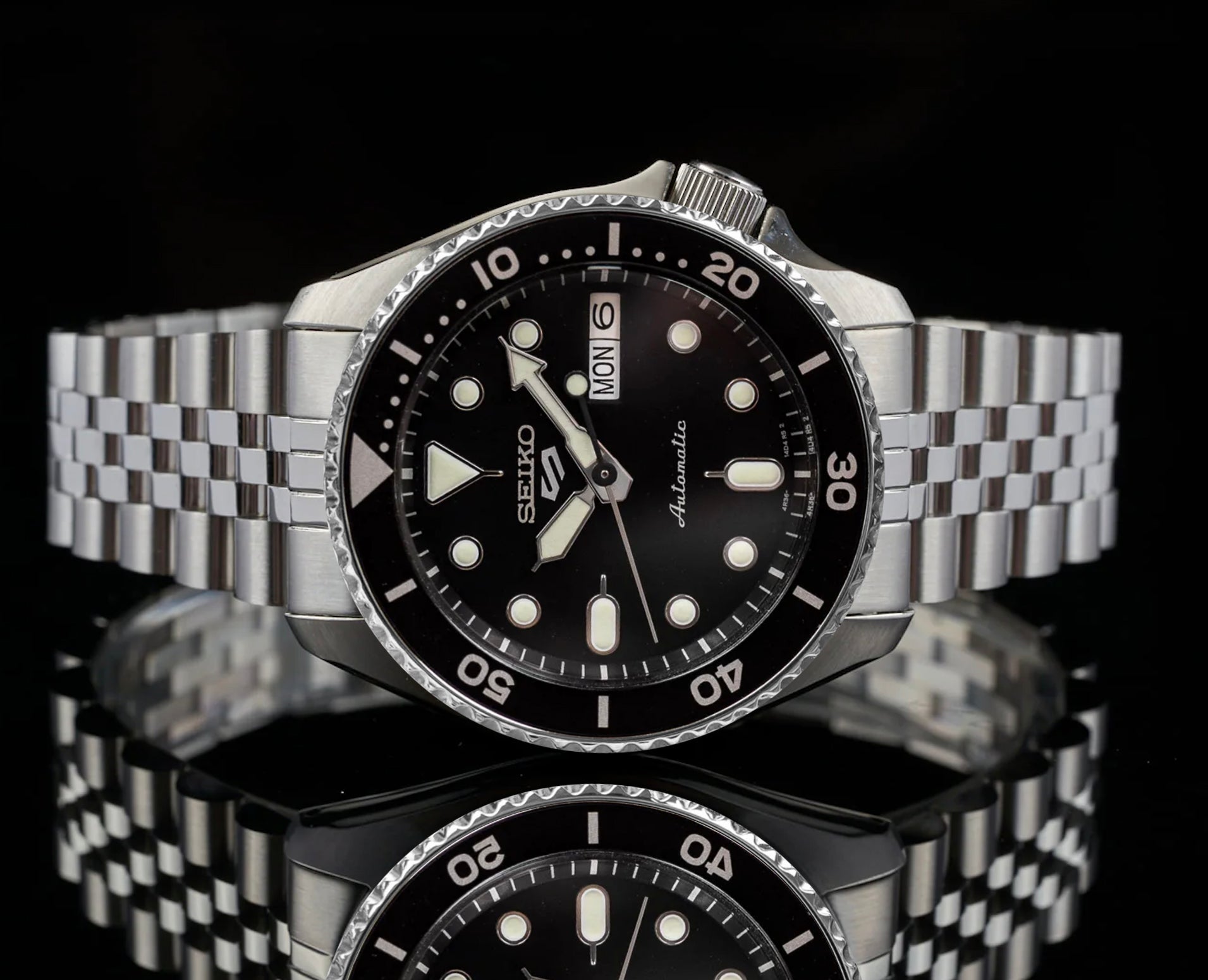Seiko 5 Sports automatic dive watch with black dial, stainless steel bracelet, rotating bezel, and date window
